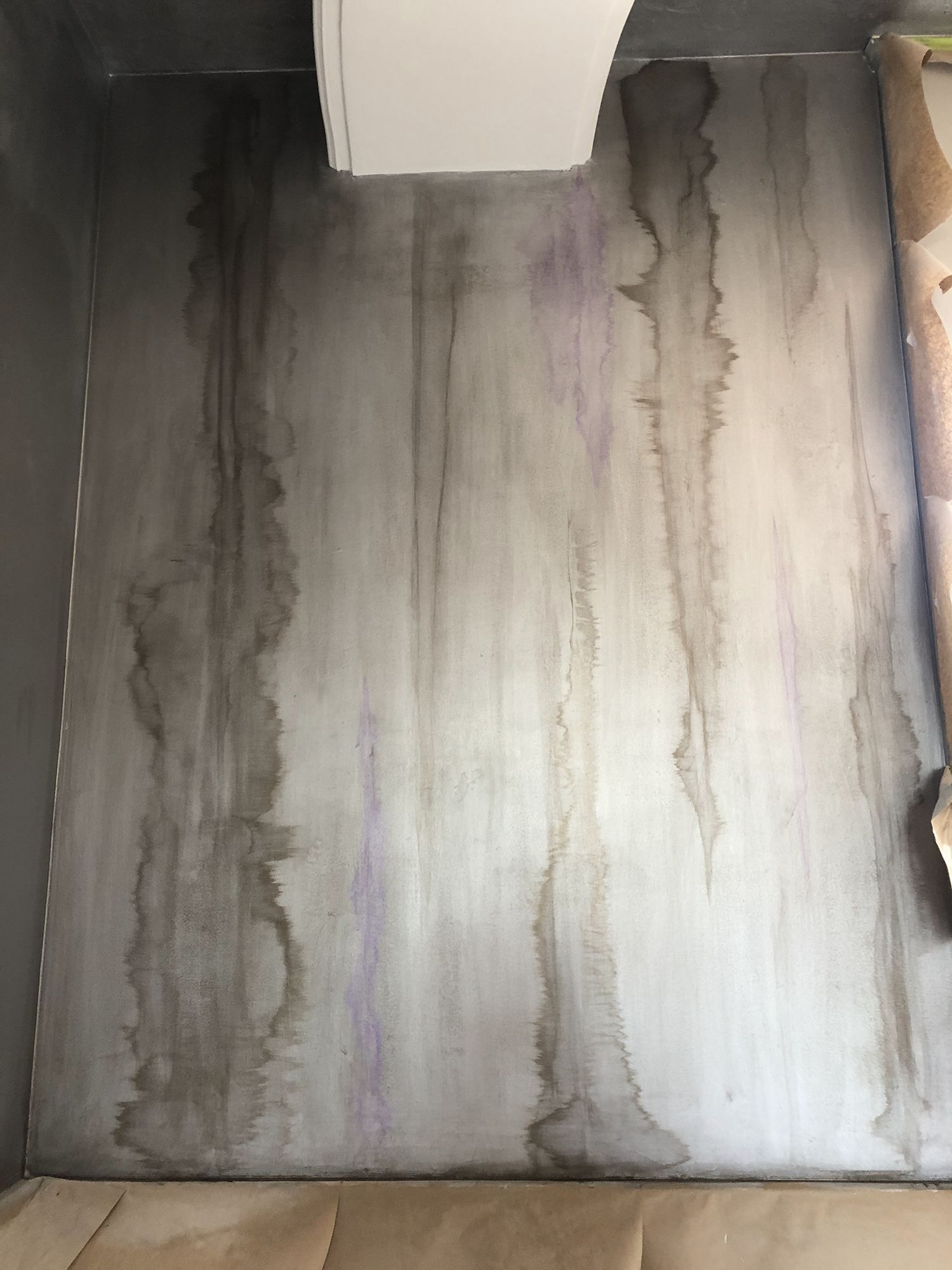 Gray wall with dark streaks from water damage, beneath a white object.