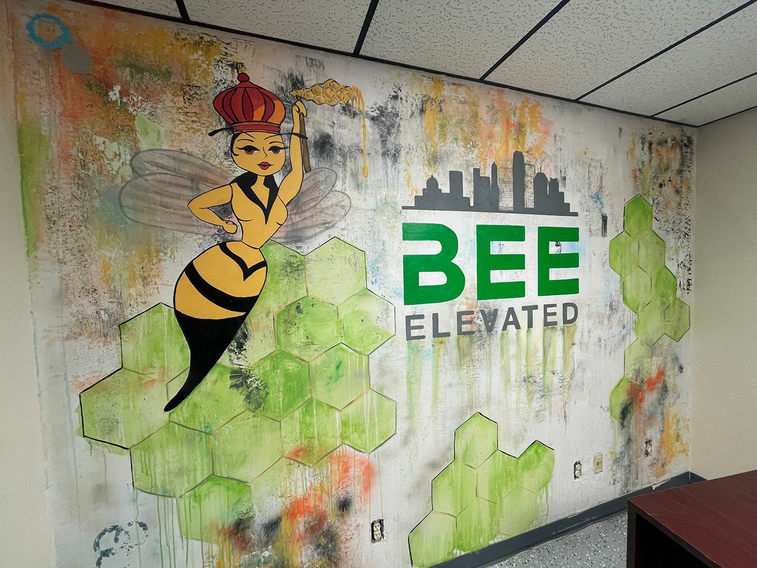 Mural with a bee-themed logo on a textured wall.