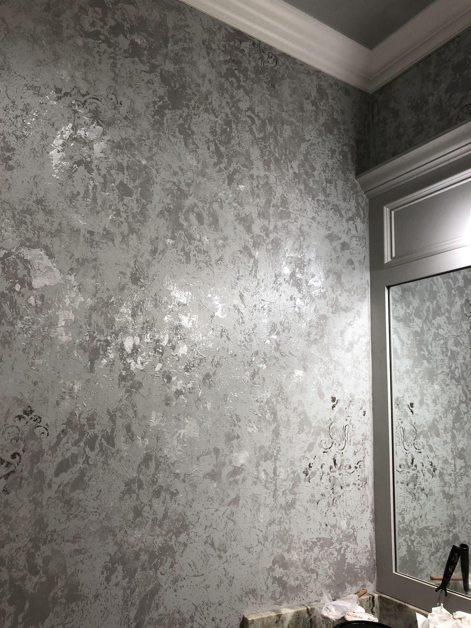 Silver textured wall with white trim and a mirror.