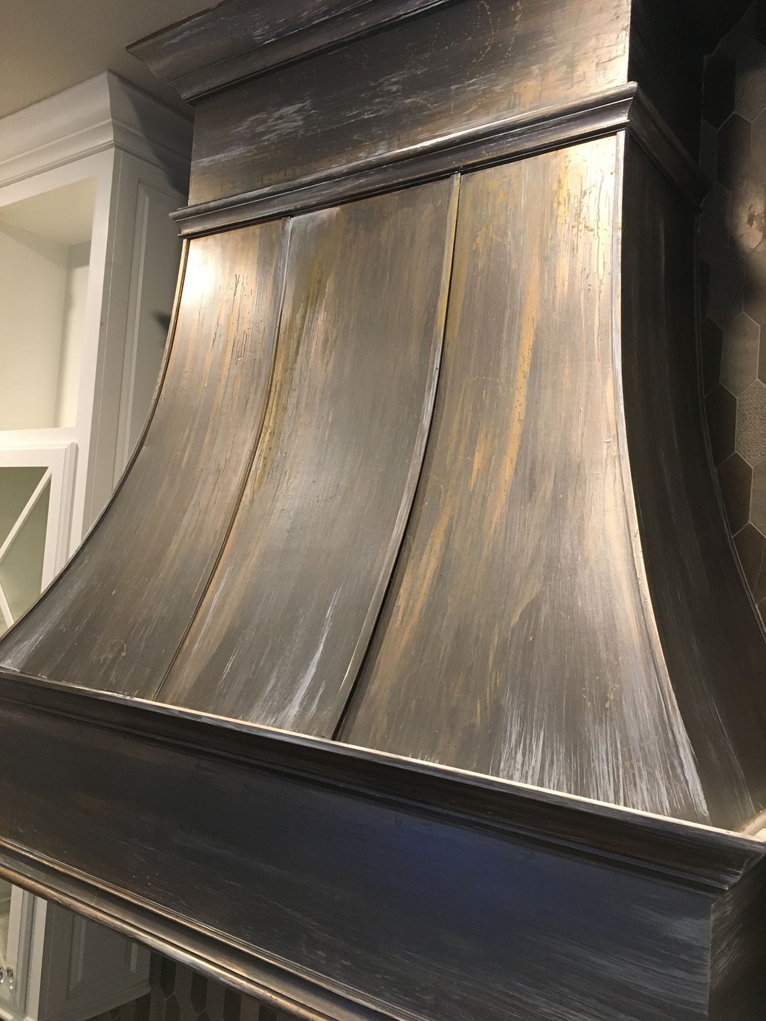 Kitchen range hood with a metallic, textured finish.
