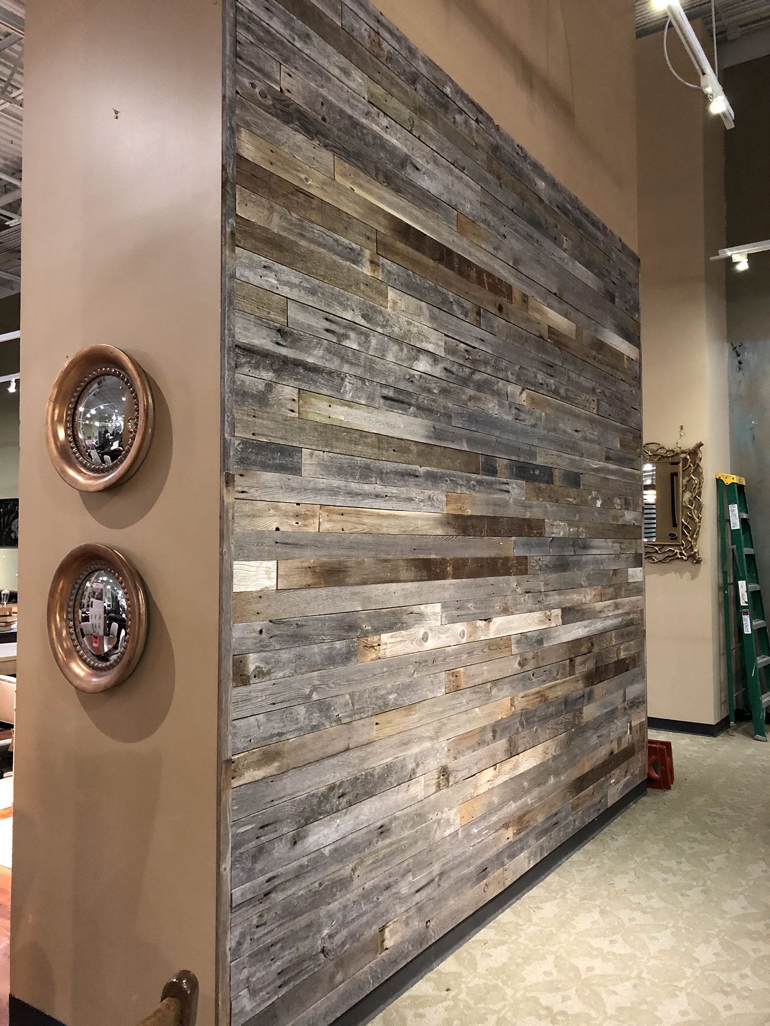 Wall covered in weathered wood planks; two round mirrors on adjacent beige wall.