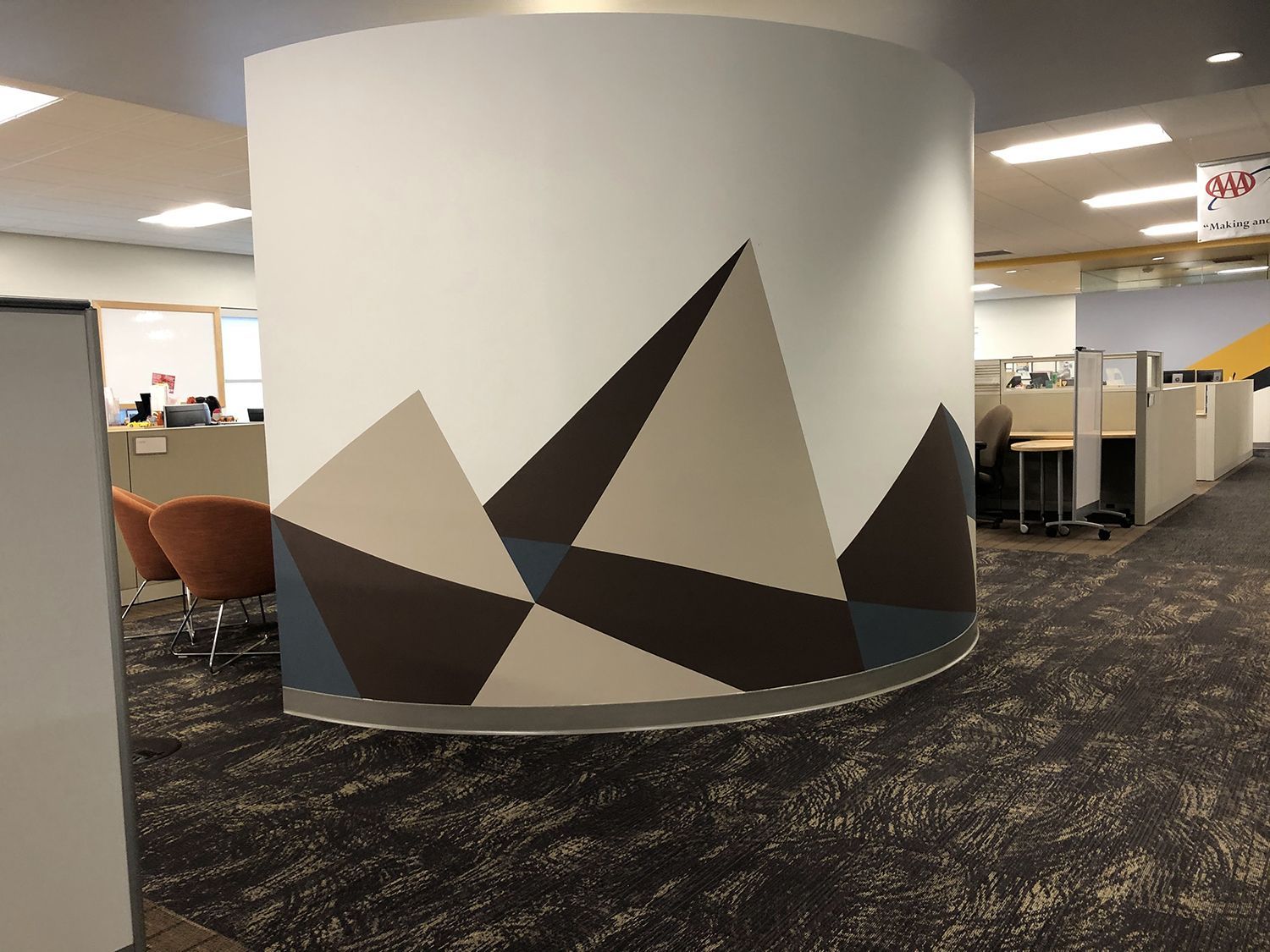 A cylindrical office wall with geometric mountain design, in an office setting.