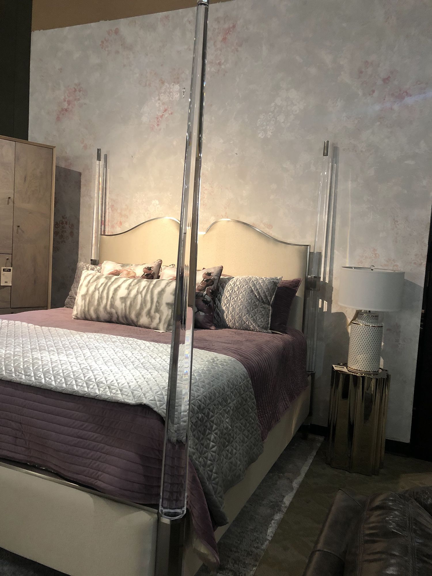 Bedroom with a purple bedspread, a white bed frame, and acrylic bed posts.