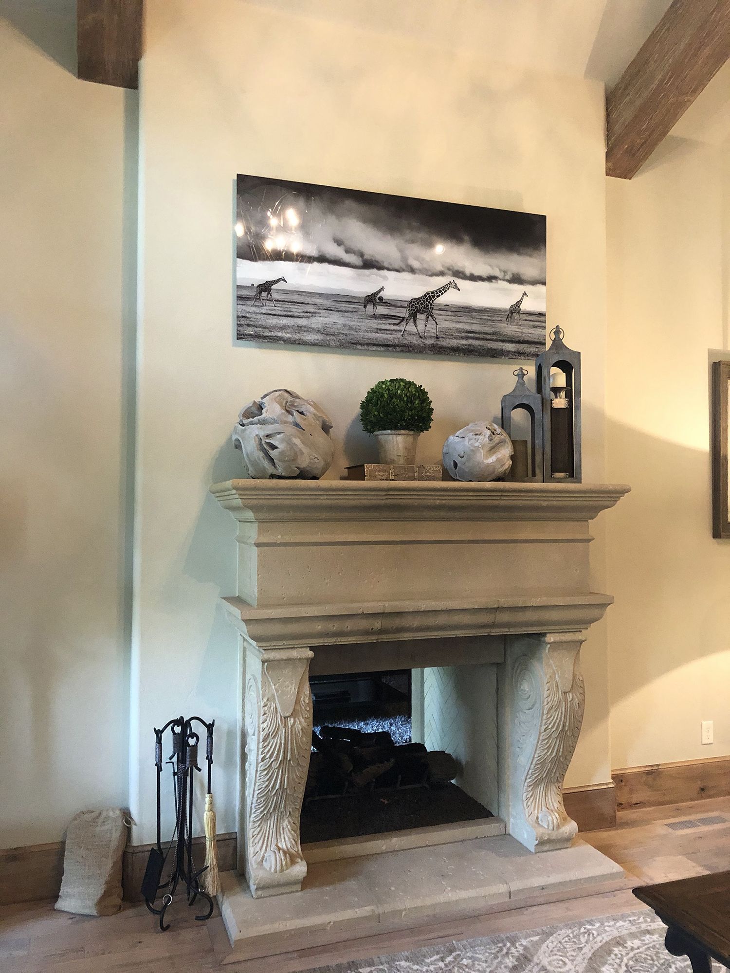 Stone fireplace with black and white artwork of giraffes, topped with decor.