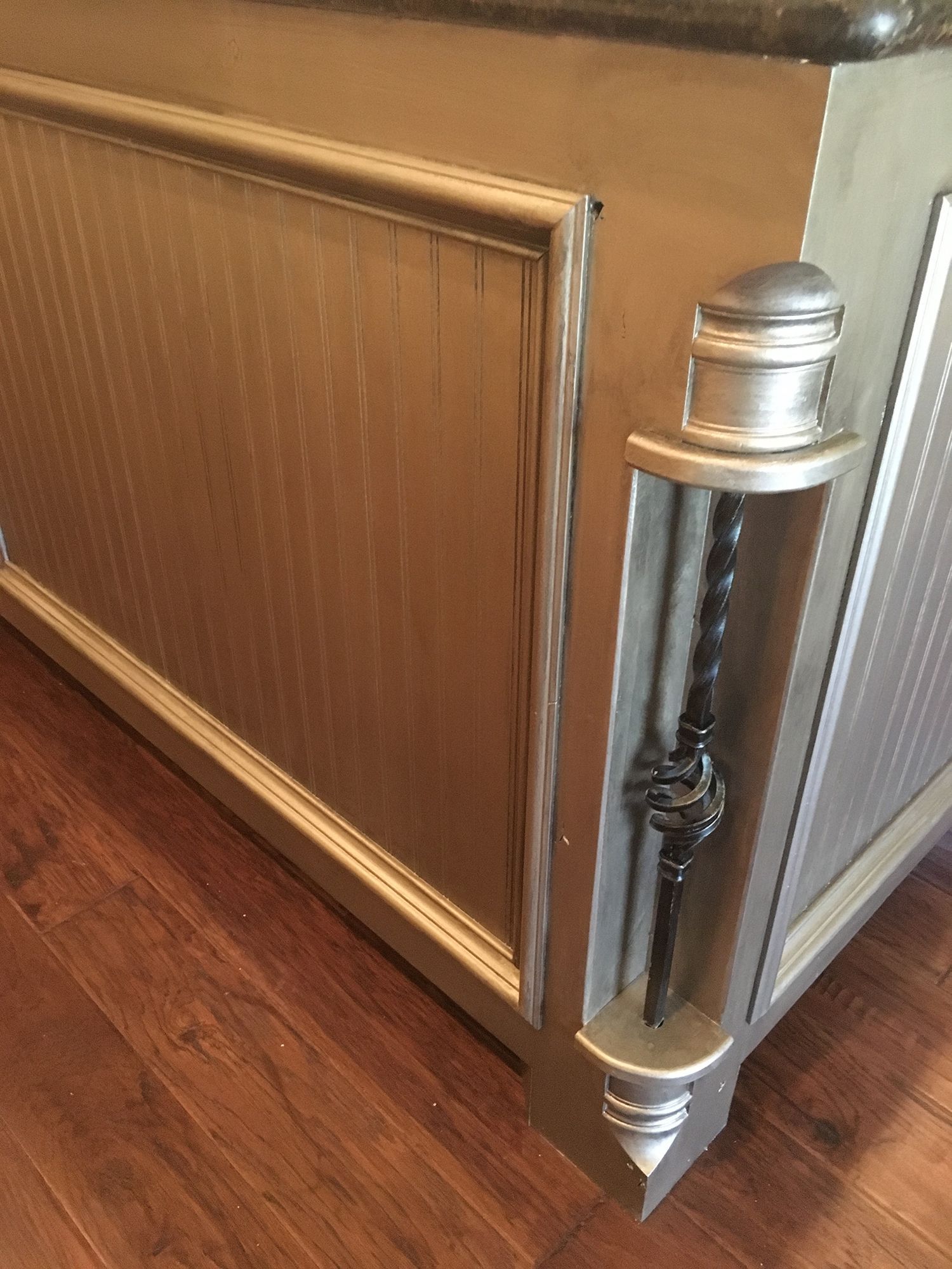 Golden cabinet with a decorative silver embellishment, on a wooden floor.