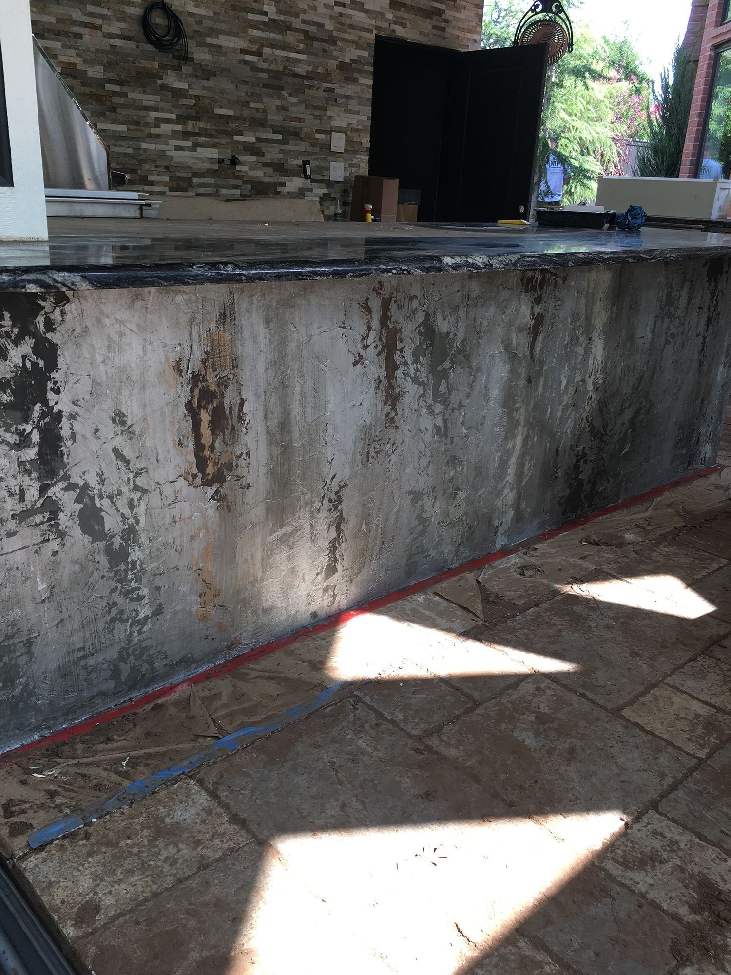 Concrete wall with peeling paint, red sealant, and stone floor.