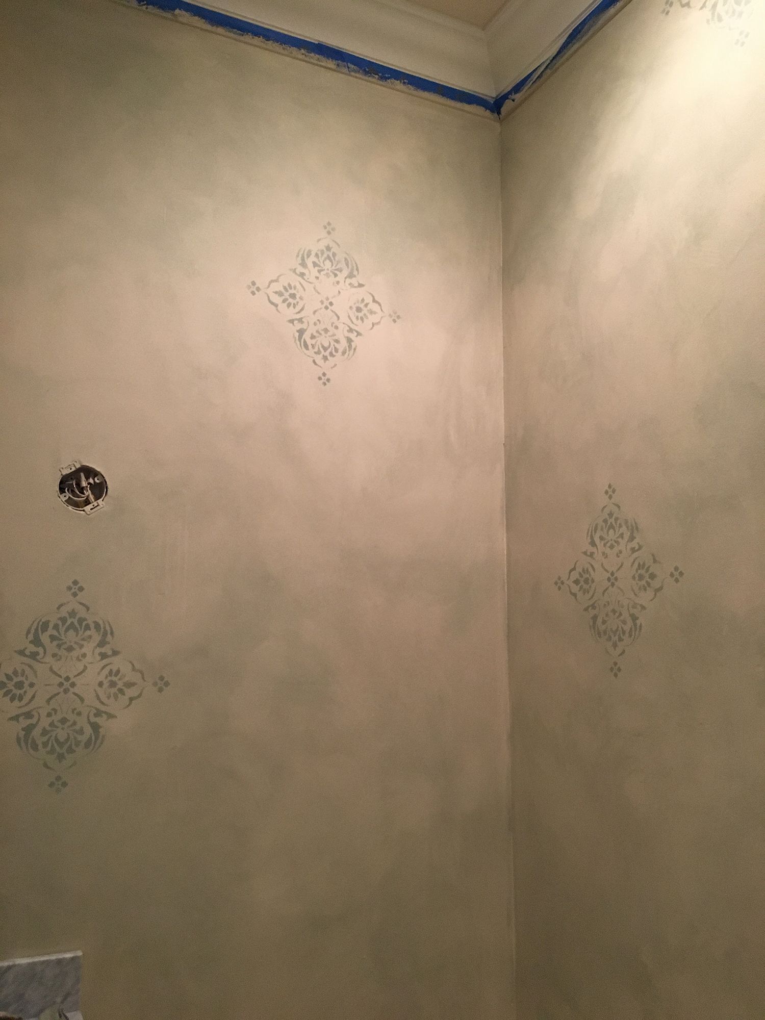 Interior corner with stenciled diamond pattern on a textured, light green wall.