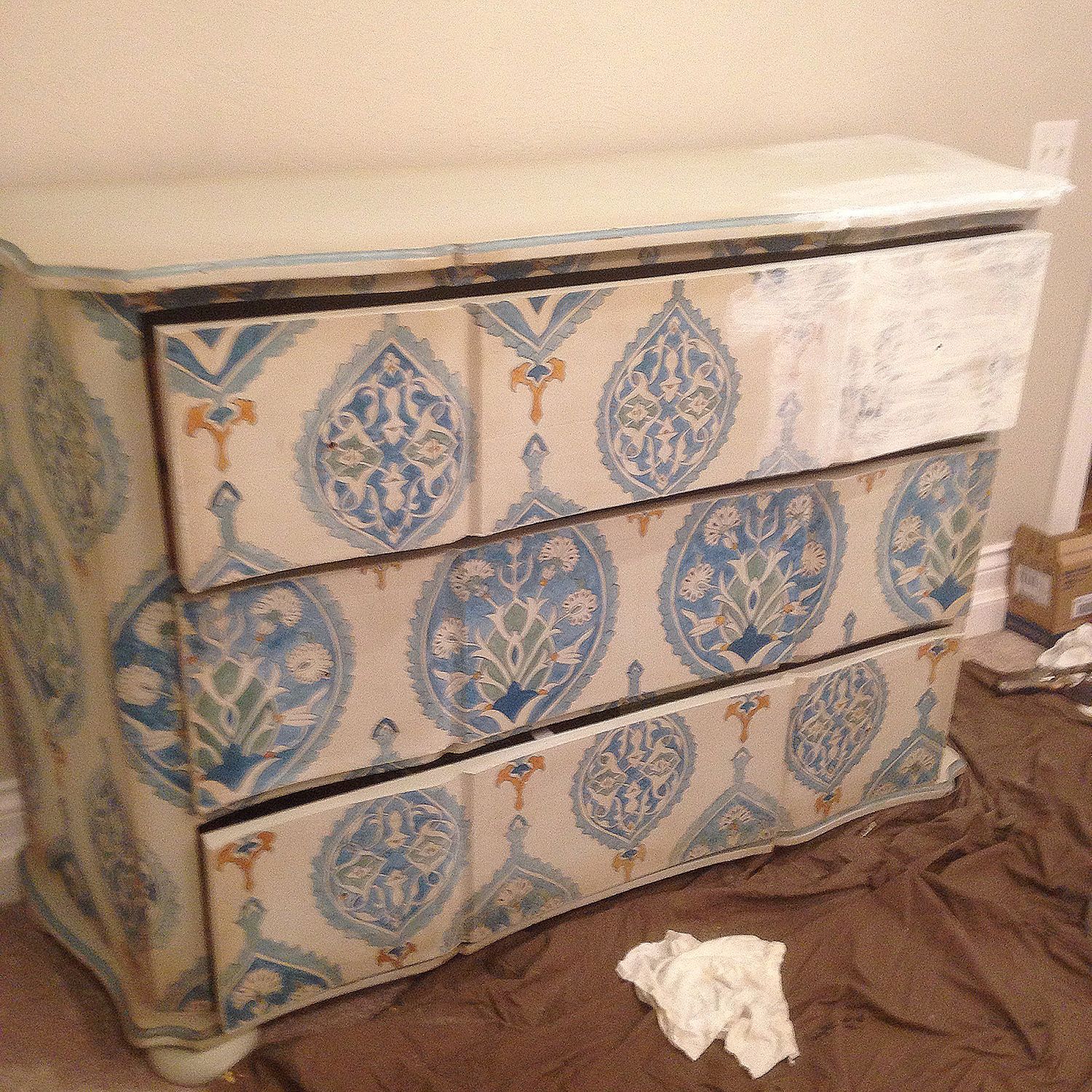 A dresser with blue and white patterned drawers against a light-colored wall.