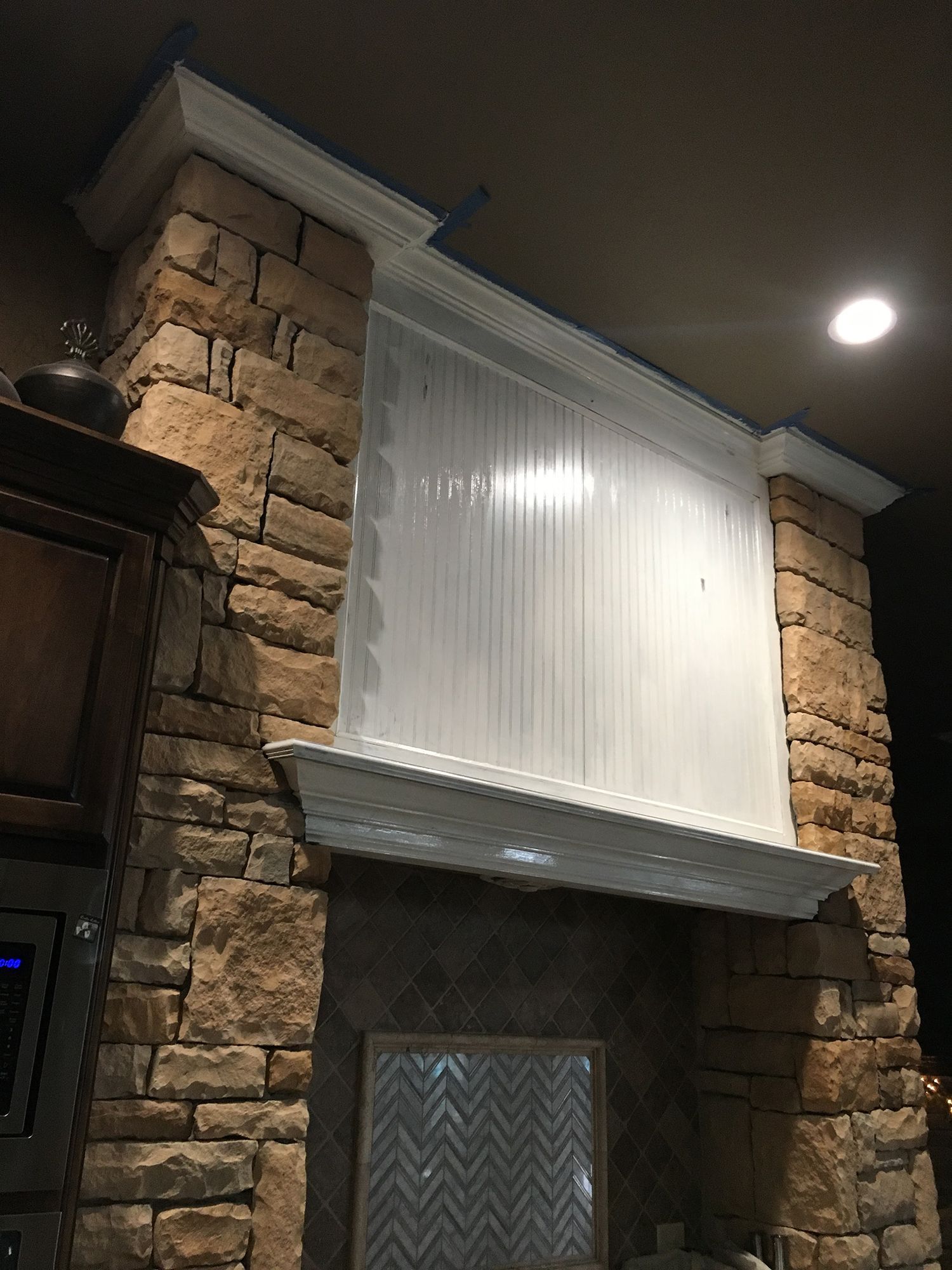 Stone fireplace with white molding, a vertical-slatted screen above the mantle, and a decorated rectangular inset.