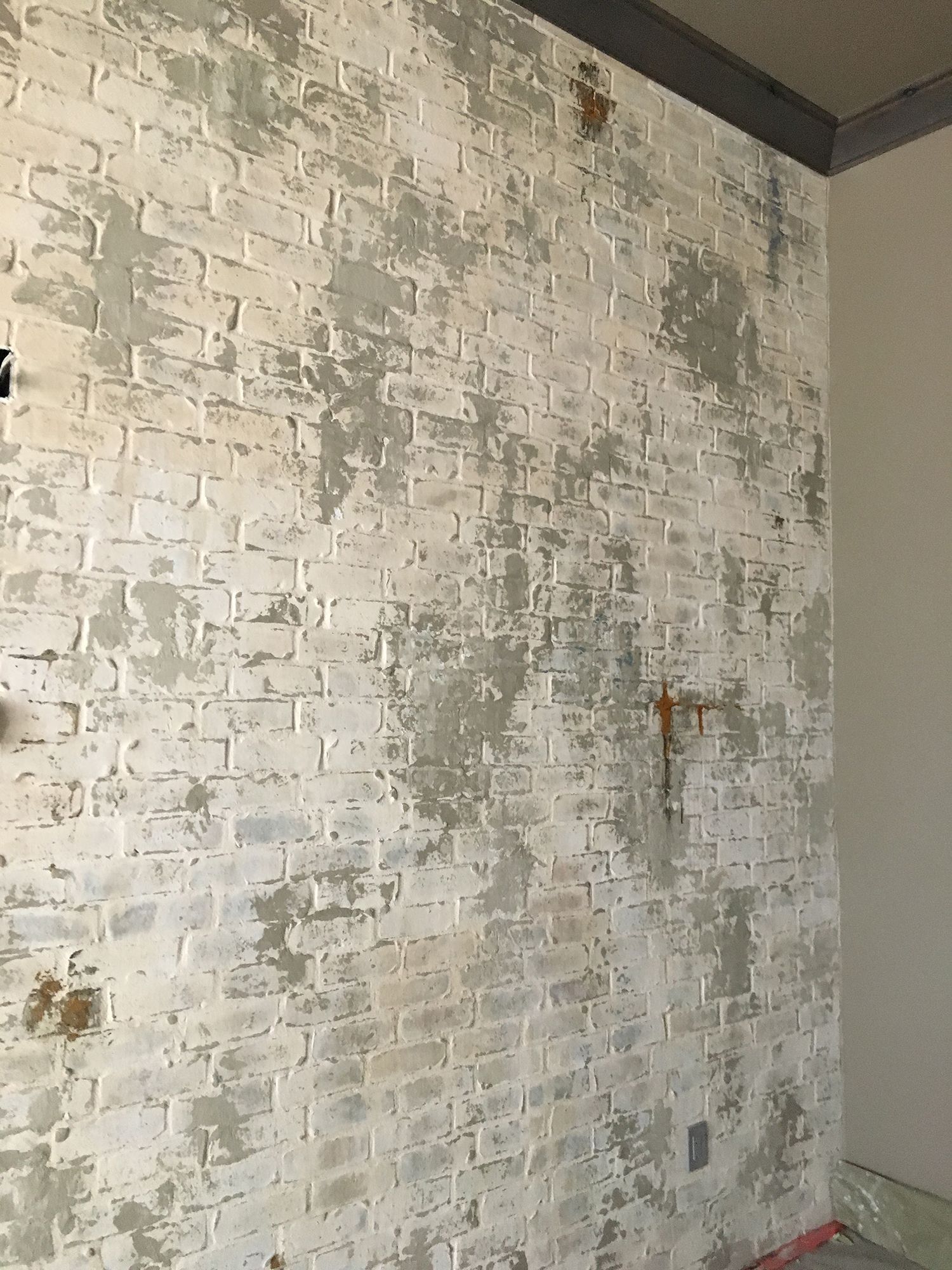 White brick wall with distressed gray and brown patches.