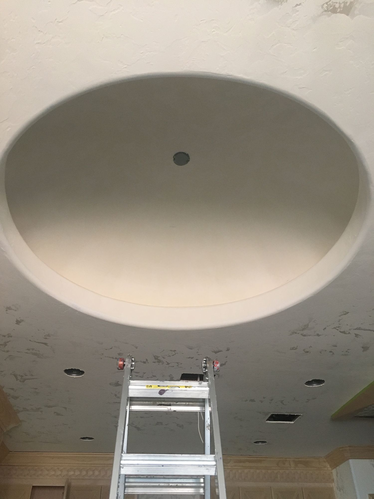 Ladder beneath a large, circular recessed ceiling. A single light is visible.