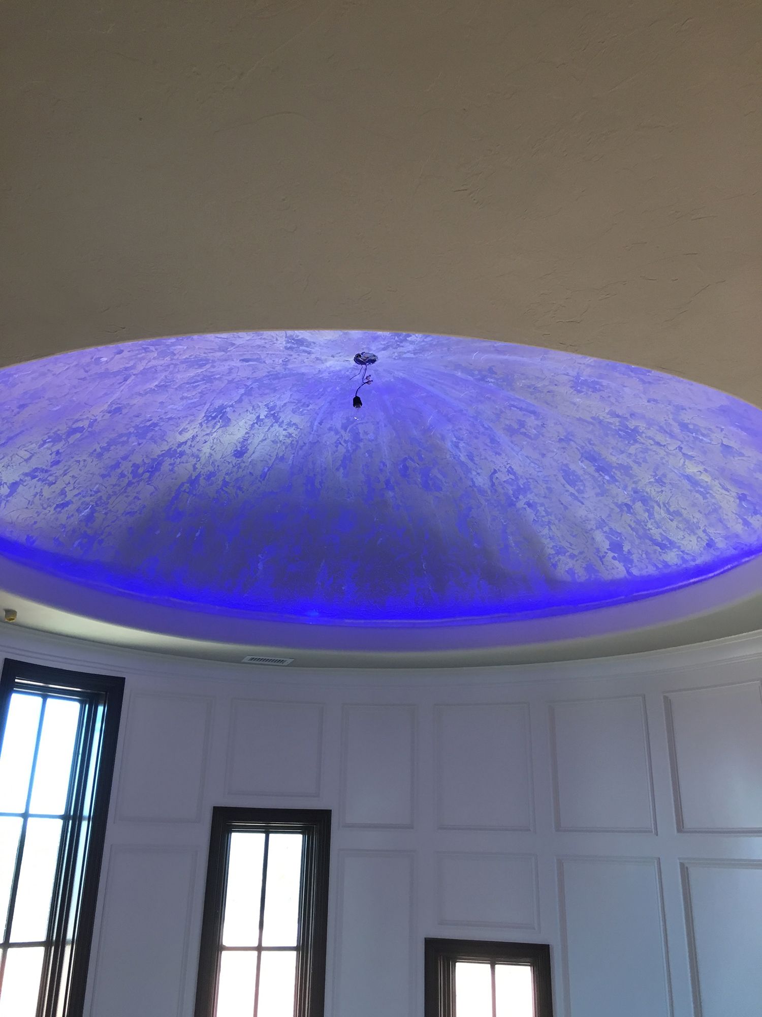 Blue-lit dome ceiling with a textured, speckled surface.  Windows line the white wall below.
