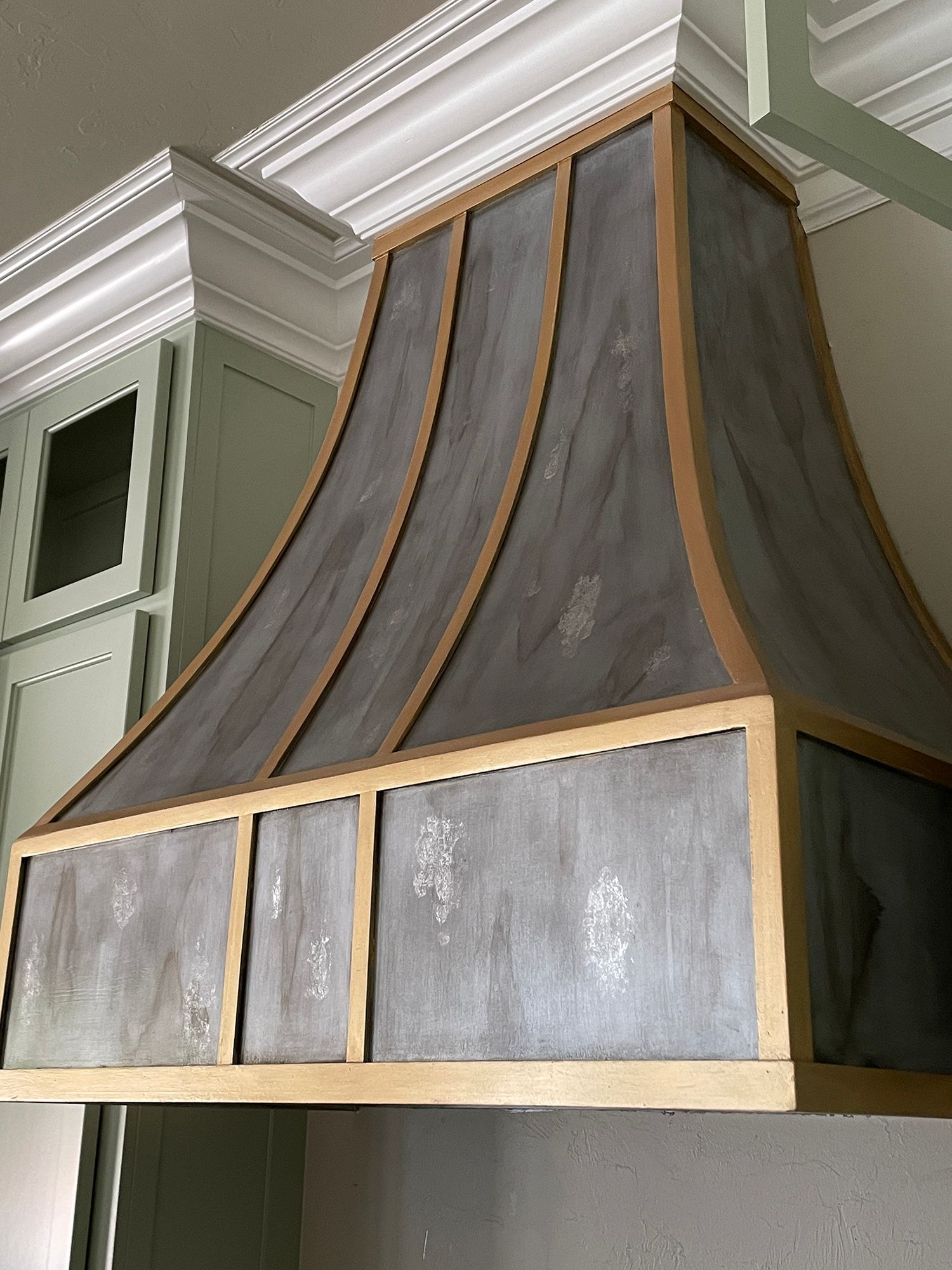 Kitchen range hood with wood trim and mottled gray panels, mounted on wall.