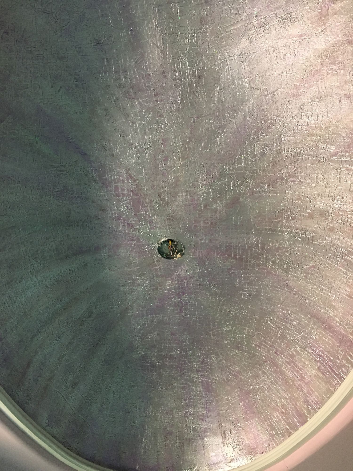 A ceiling with a swirl of purple and silver paint and a center light fixture.