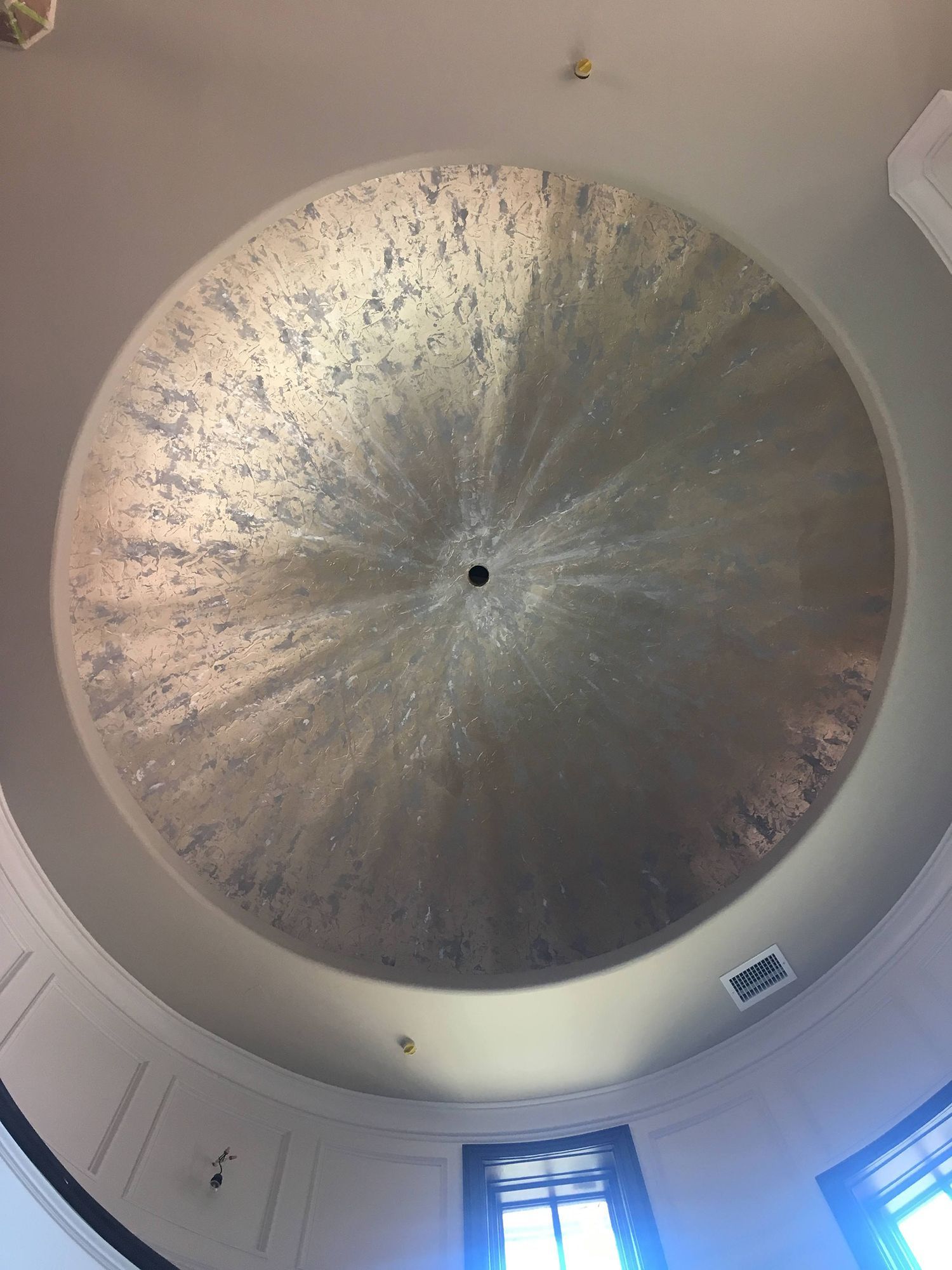 Silver-painted, domed ceiling with a central, dark square; set in a white and gray room, viewed from below.