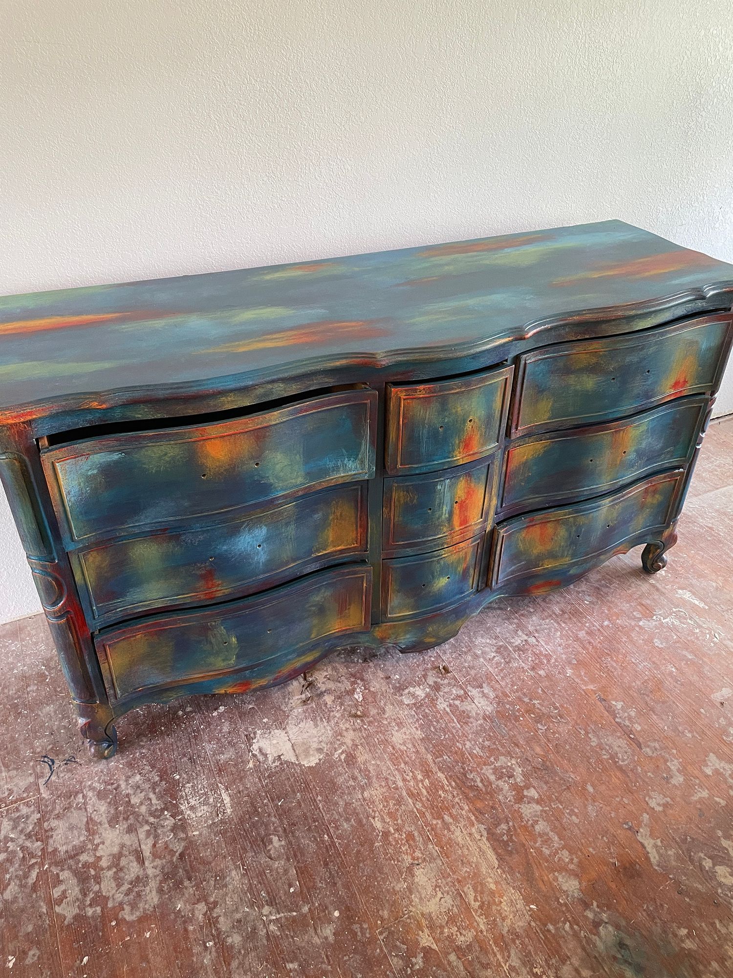 Distressed blue and orange painted dresser with six curved drawers.