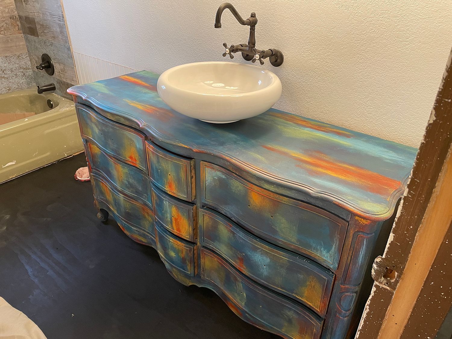 Blue and orange painted dresser with a white bowl sink and faucet.
