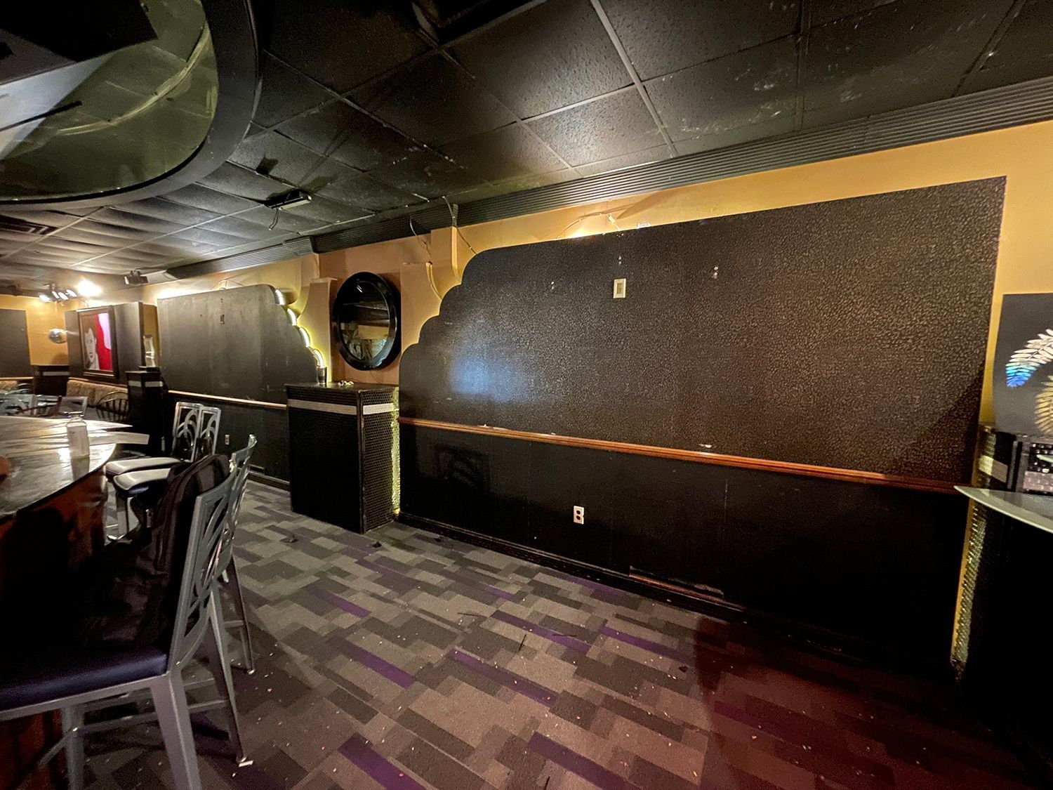 Interior of a damaged venue with exposed walls, dark ceiling, and a partially visible bar and seating.