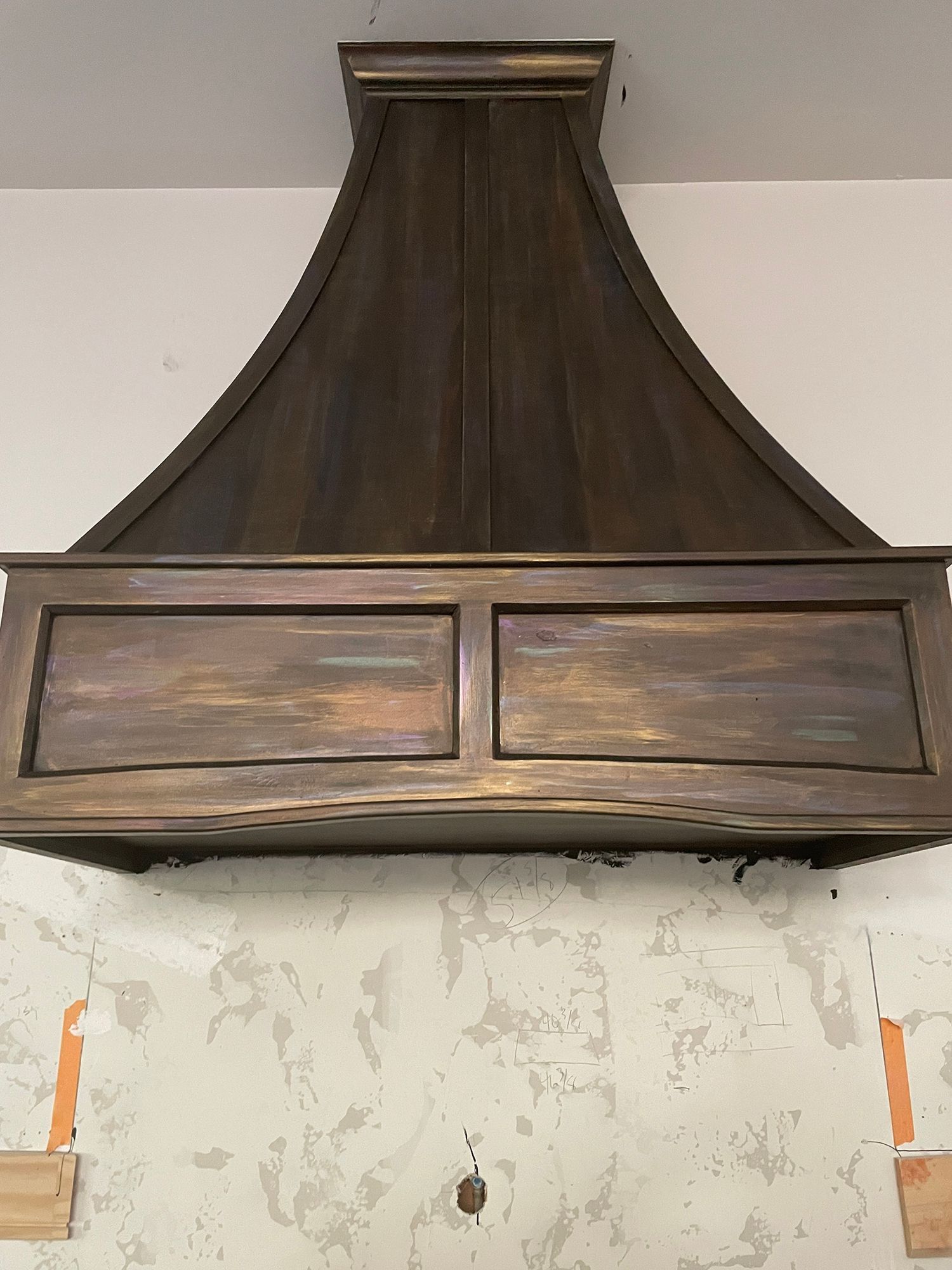 Dark wood range hood on a textured wall.