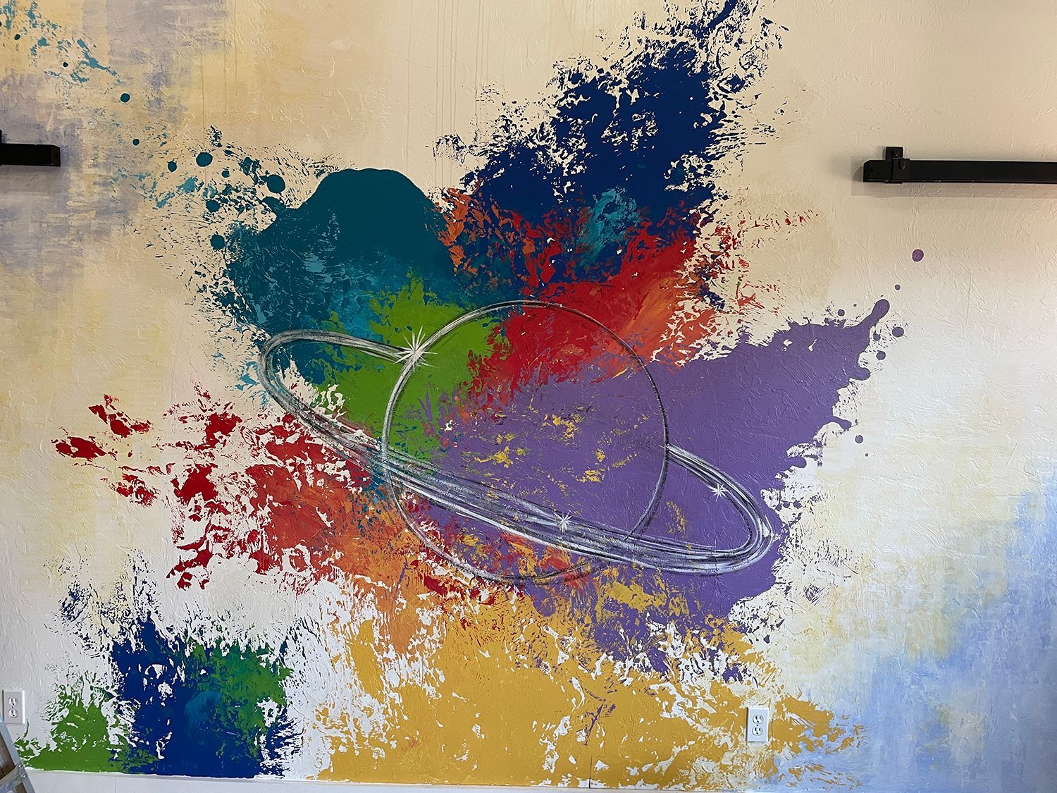 Abstract art, colorful paint splatters, silver ring design on off-white background.