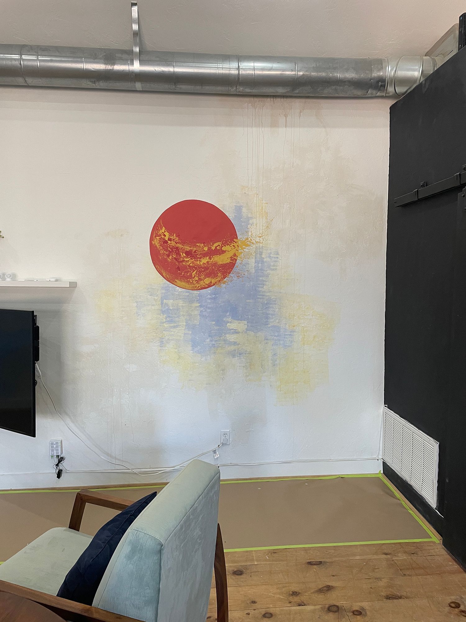 Wall mural of a red and yellow planet with a blue and yellow background on a white wall.