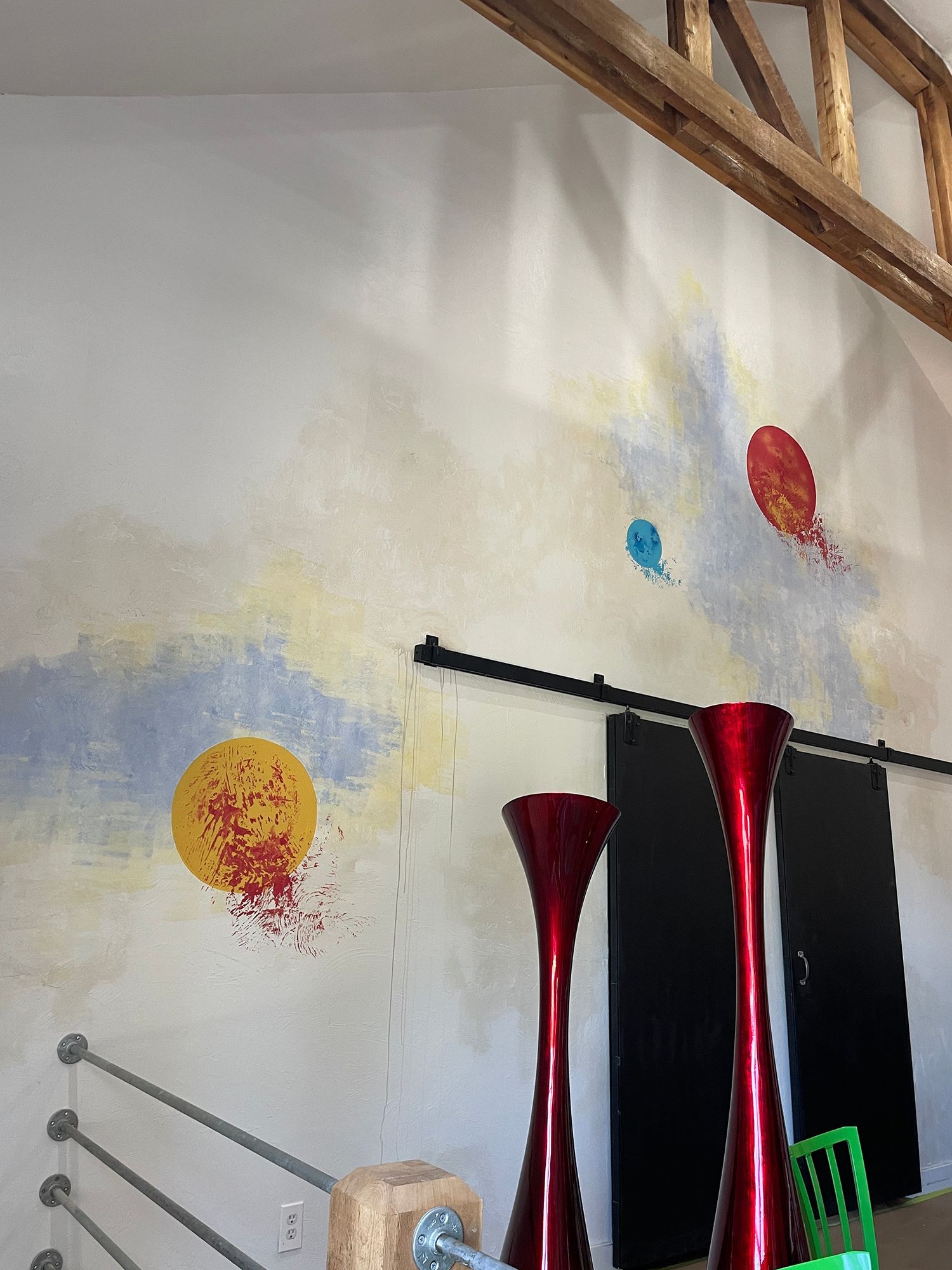 Wall mural with painted planets, red vases, and a sliding black door.