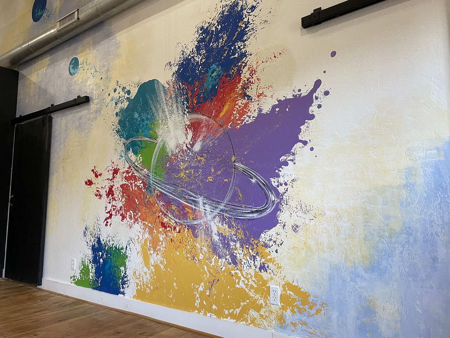 Colorful abstract mural on a white wall, splashes of paint in rainbow hues.