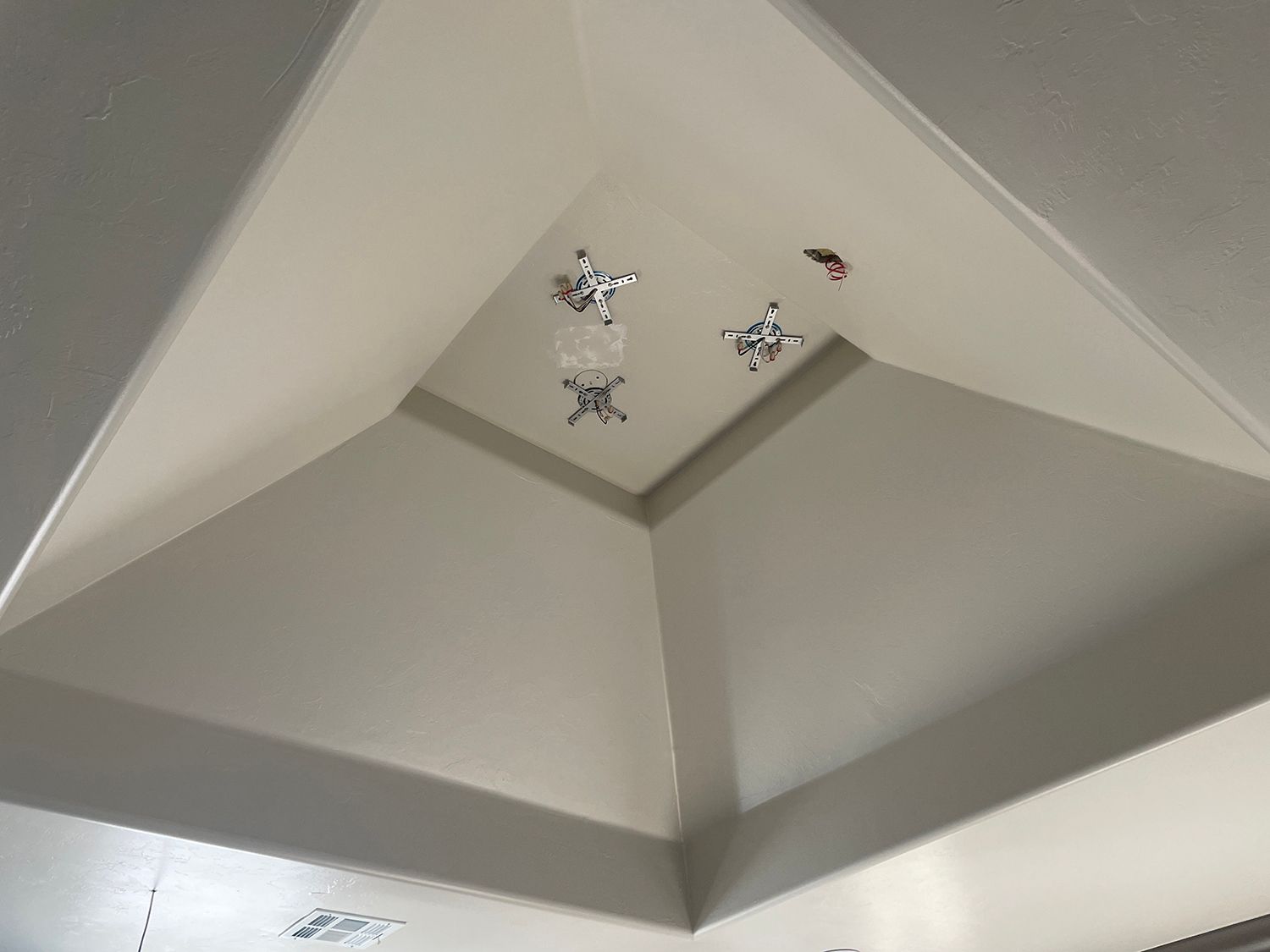 Ceiling with four silver decorative star ornaments and a single red ornament.