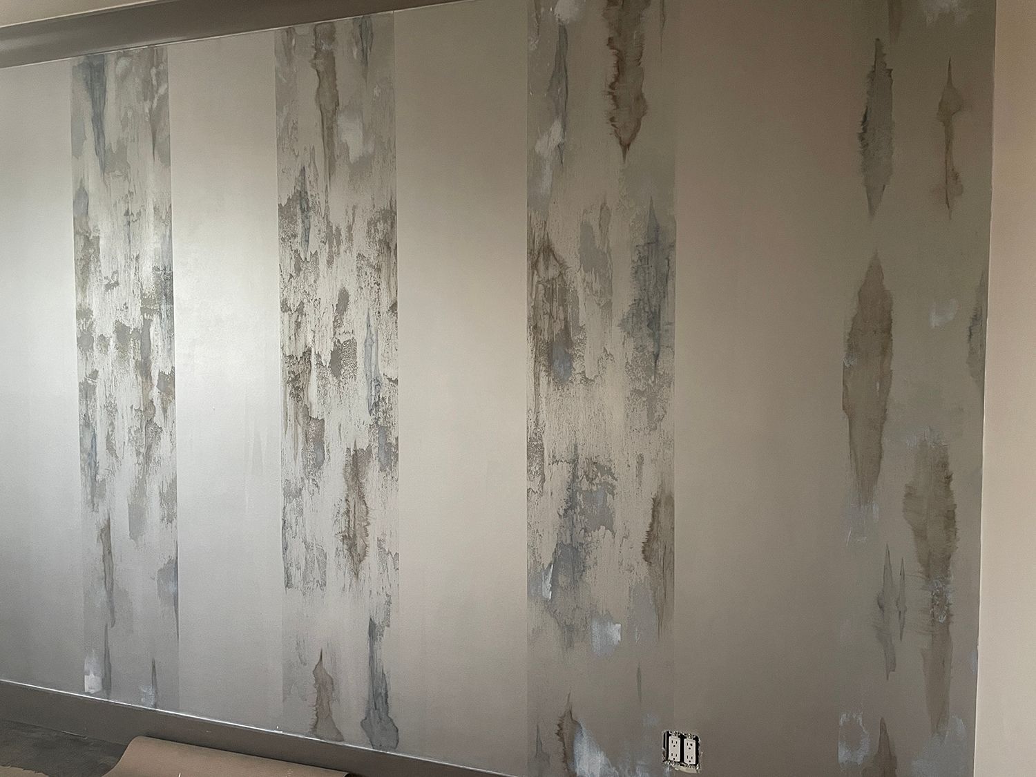 Interior wall with vertical sections of peeling paint and exposed plaster.