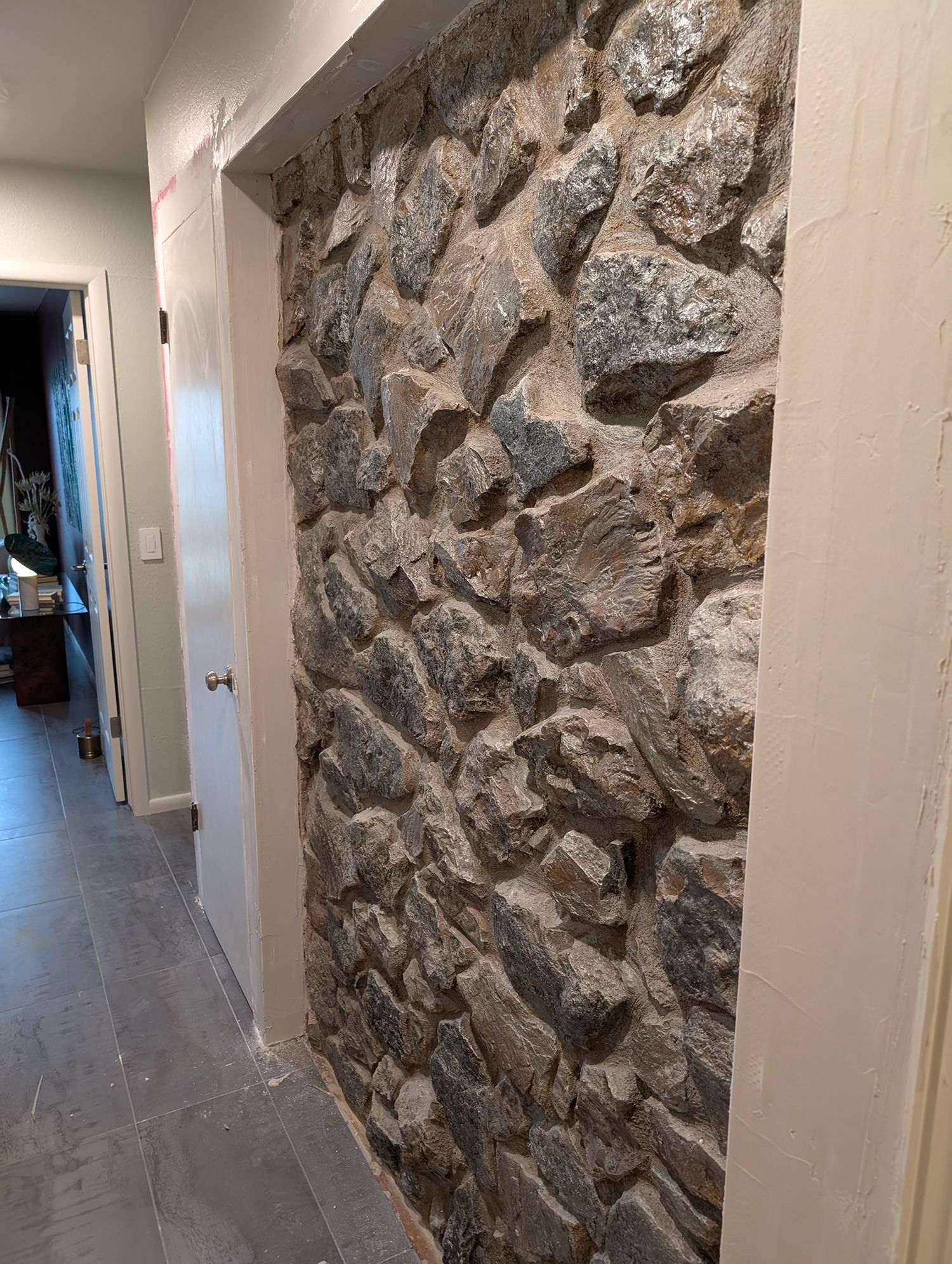 Stone wall section framed by white trim in a hallway.
