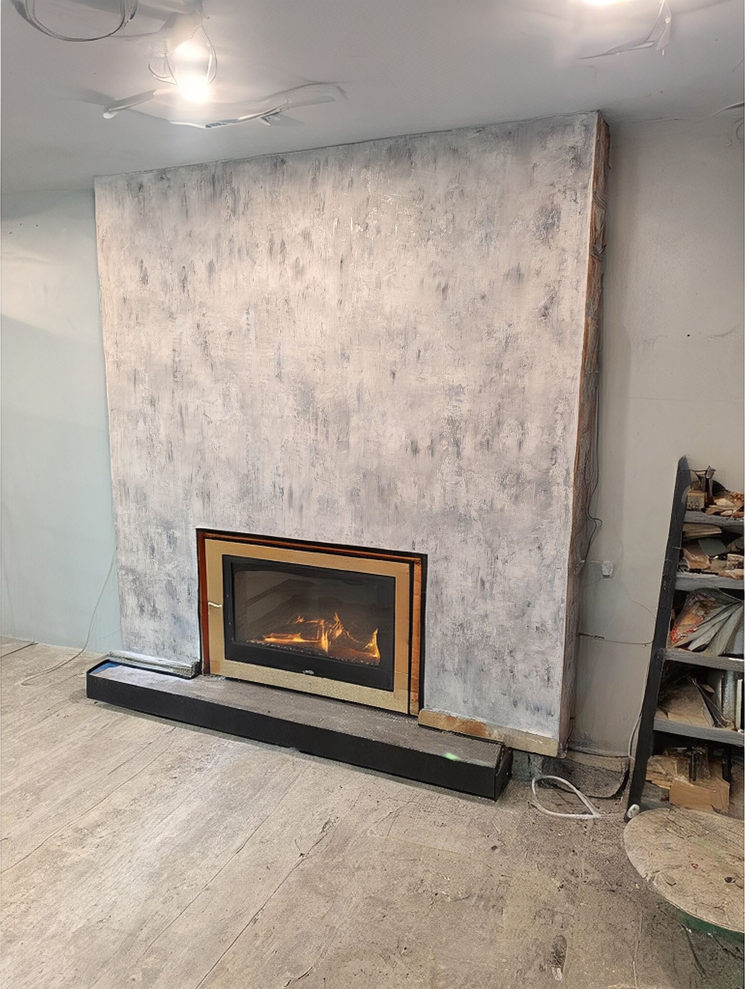 Fireplace with a concrete-textured wall. Flame inside with a dark frame. A black base on the floor below.