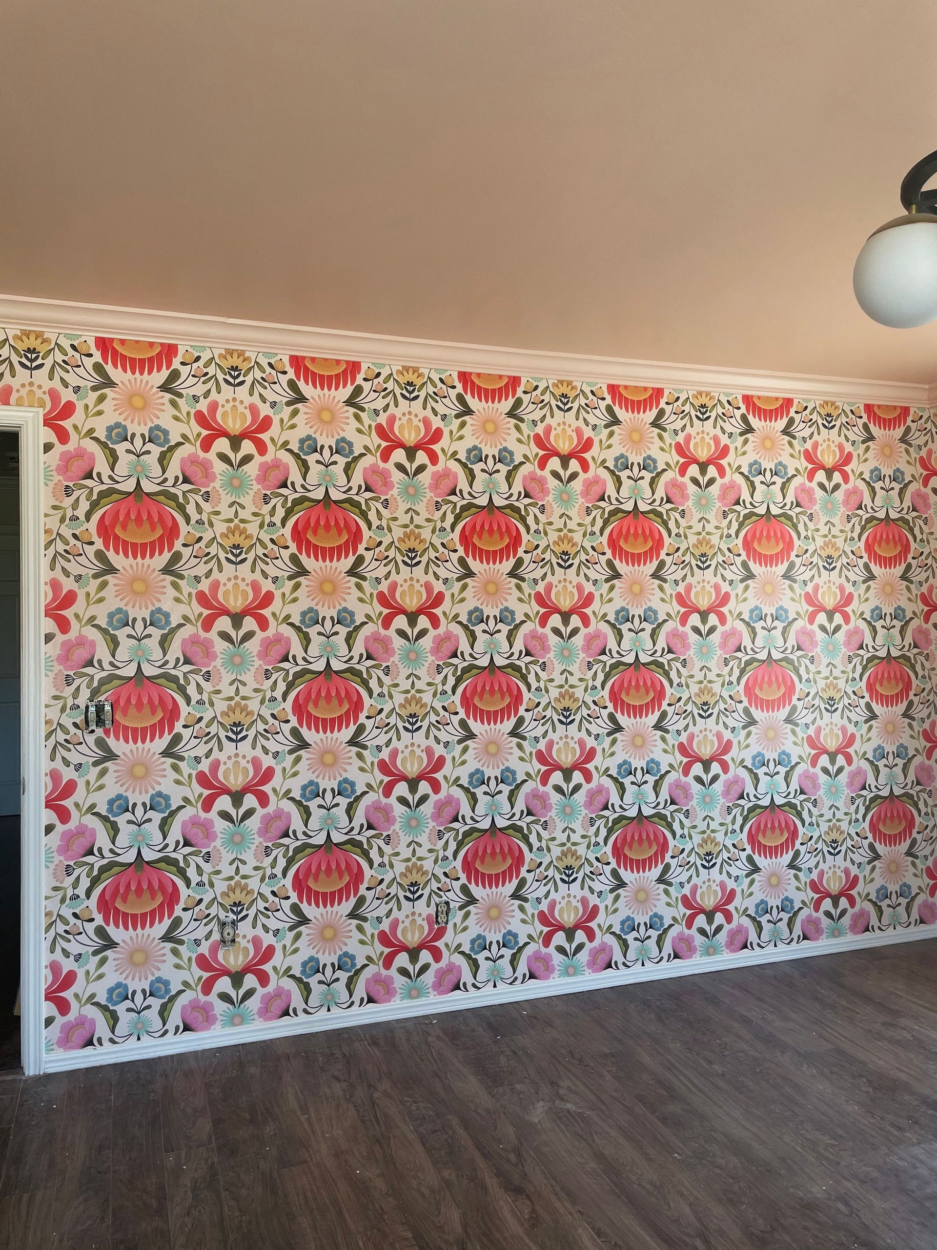 Room with floral wallpaper, white trim, and a globe light fixture.