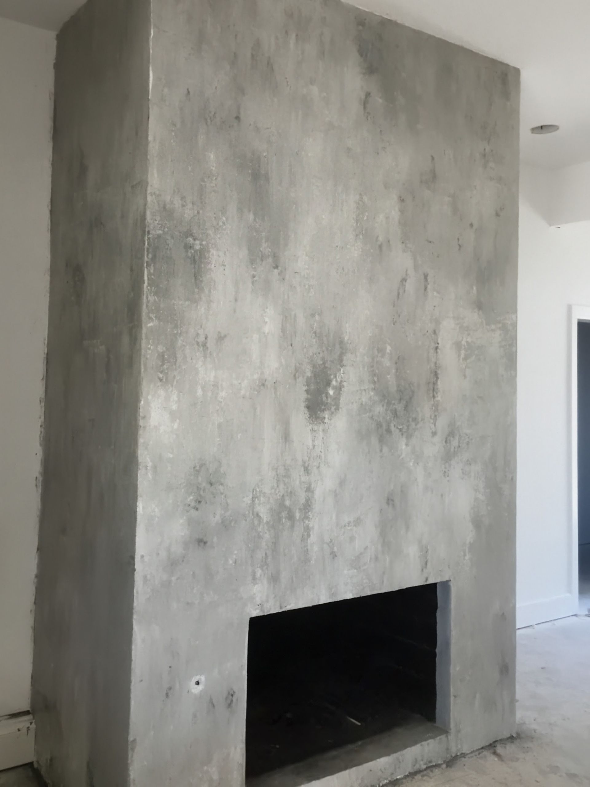 Gray concrete fireplace with dark opening and textured surface.