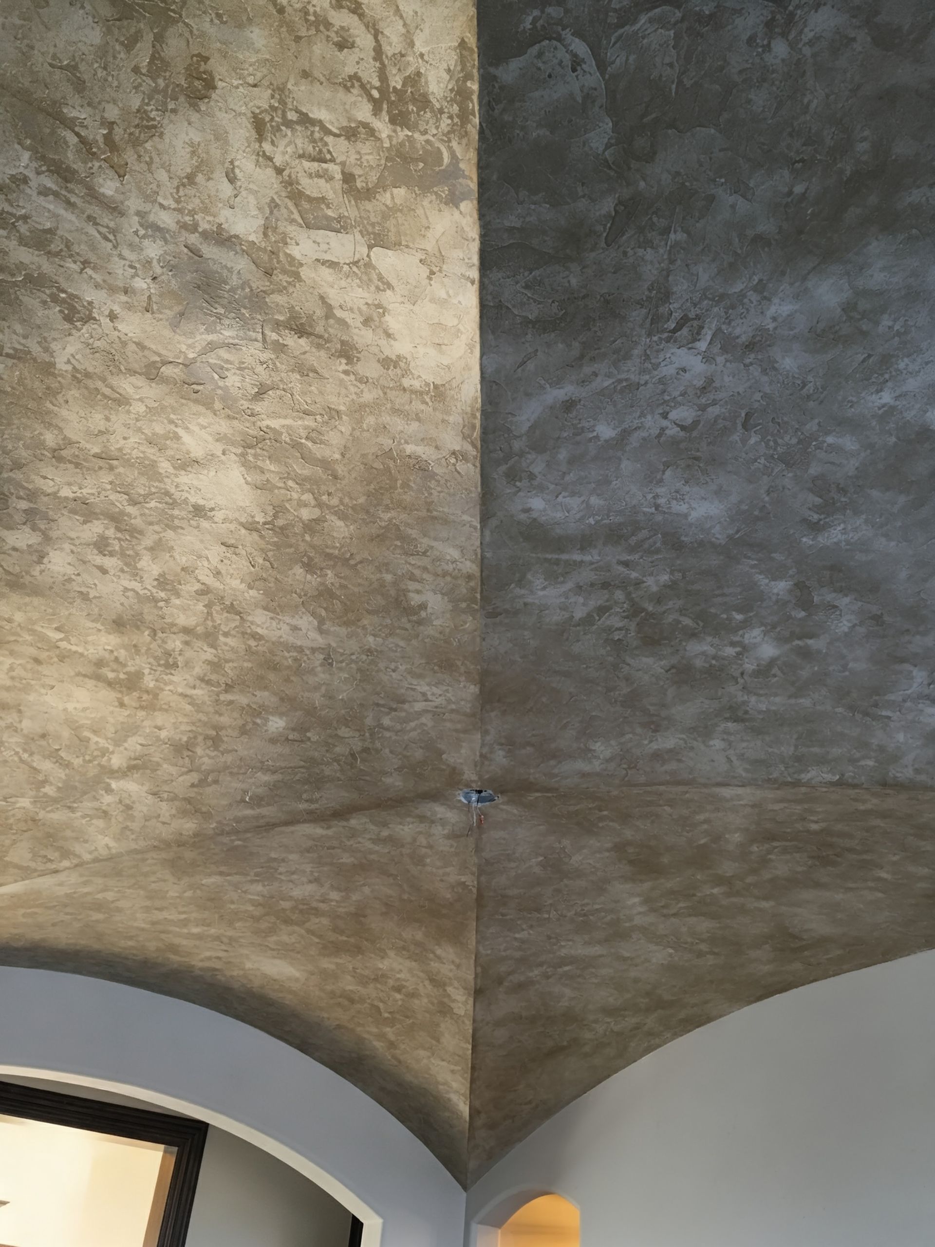 Textured, vaulted ceiling with a two-tone, mottled gray finish; corner view.
