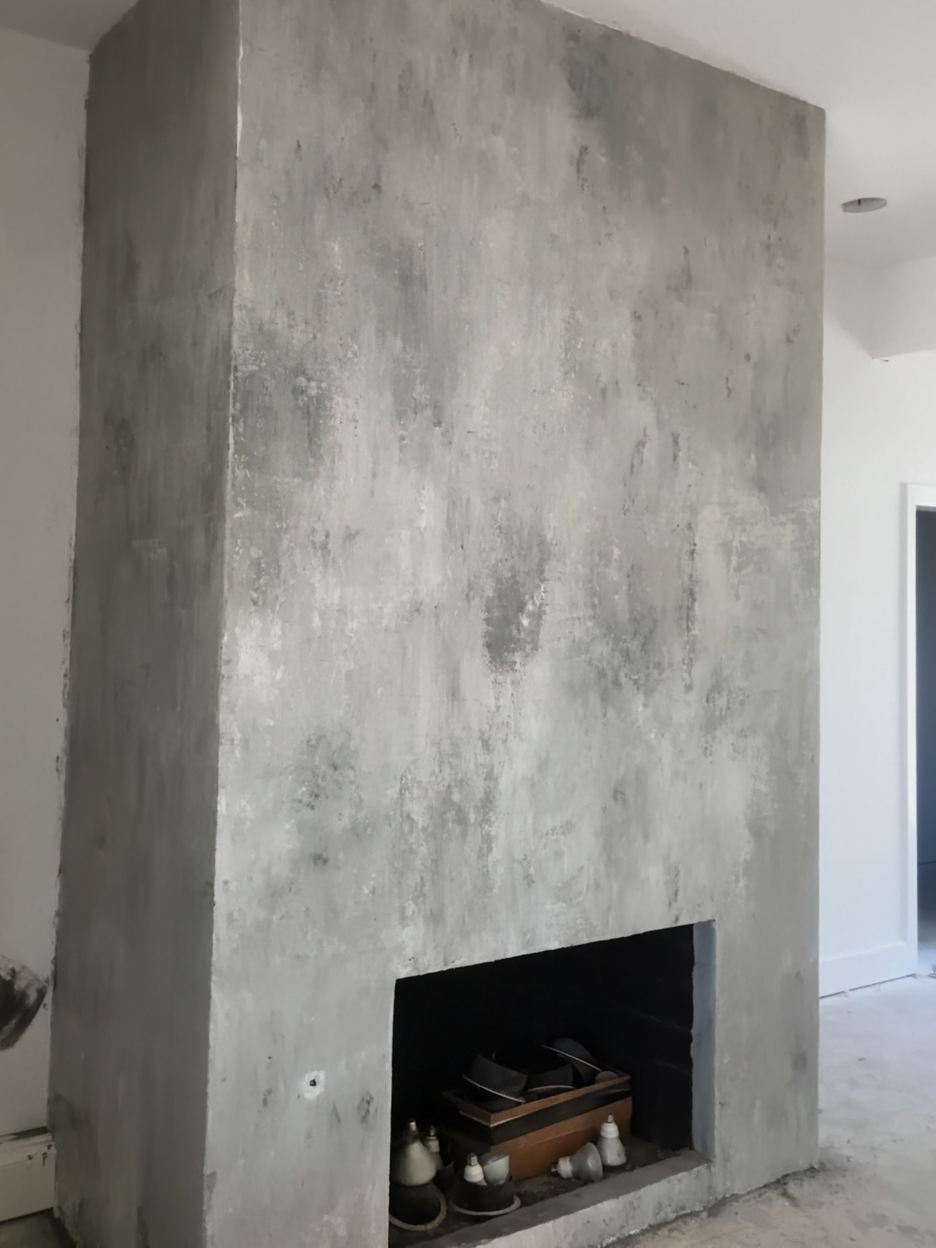 Gray concrete fireplace with a rectangular opening and a light-colored, mottled finish.