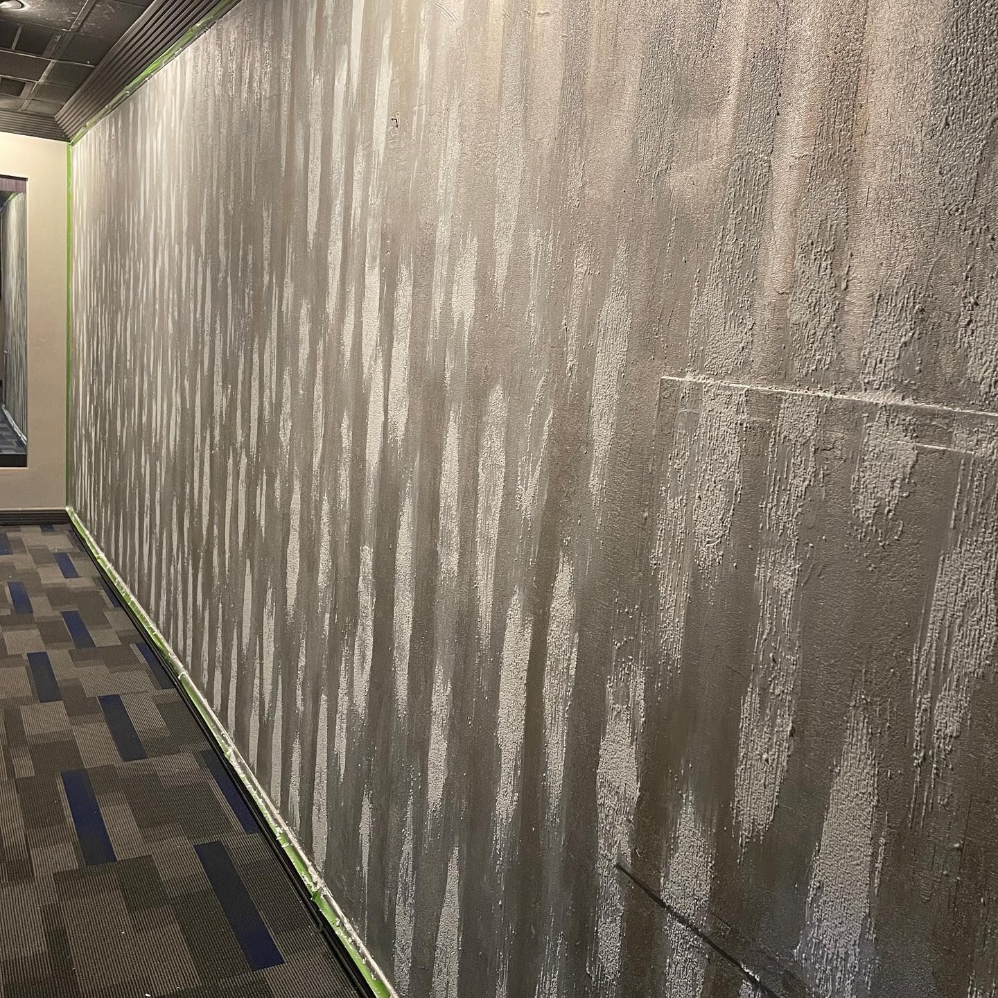 Long hallway with textured gray wall and striped carpet.