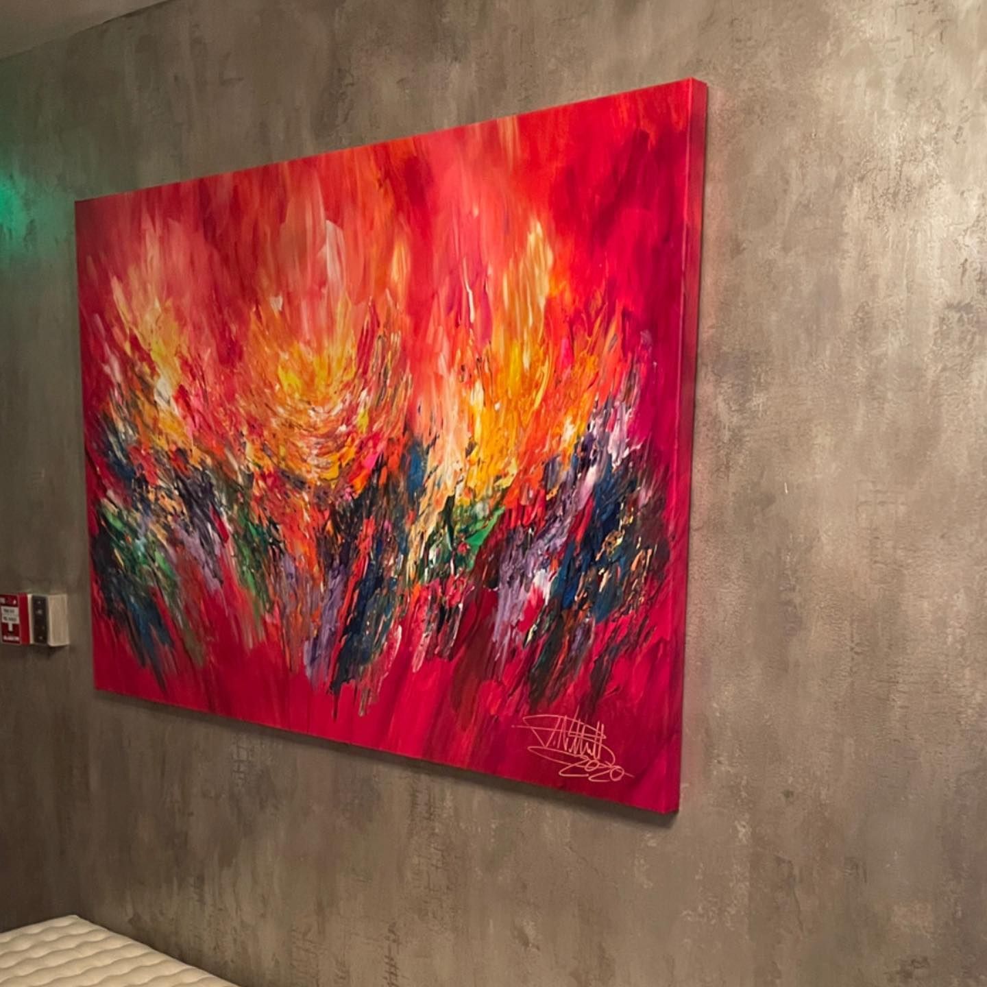 Abstract art painting, fiery red, orange, blue, and green brushstrokes on a wall.