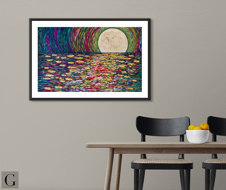Moon over water art framed on a wall above a table with chairs and a bowl of lemons.