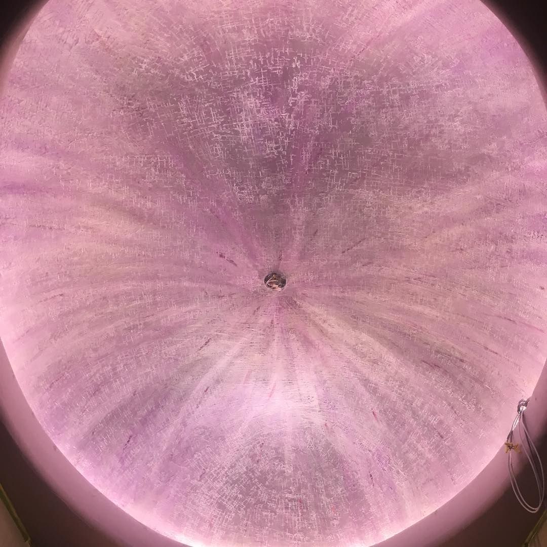 Pink, circular ceiling with radiating light patterns, centered by a small light fixture.