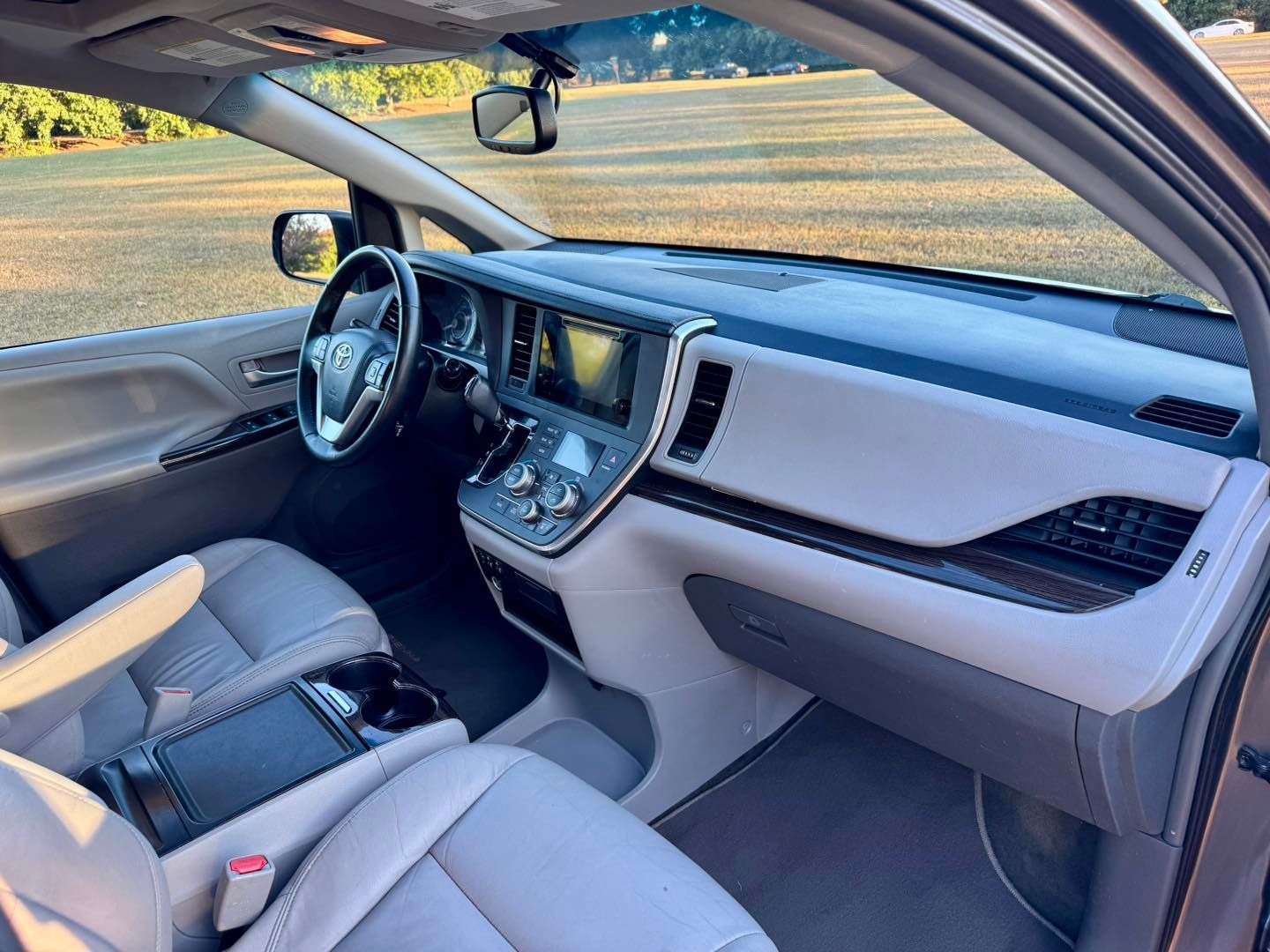 Interior view of a beige Toyota Sienna minivan with a dashboard, steering wheel, and seats visible.