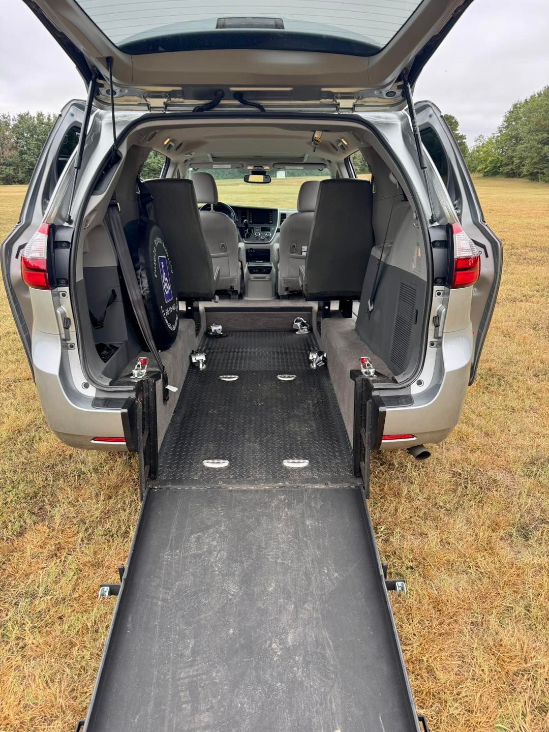 Silver accessible van interior with ramp deployed, two front seats visible.