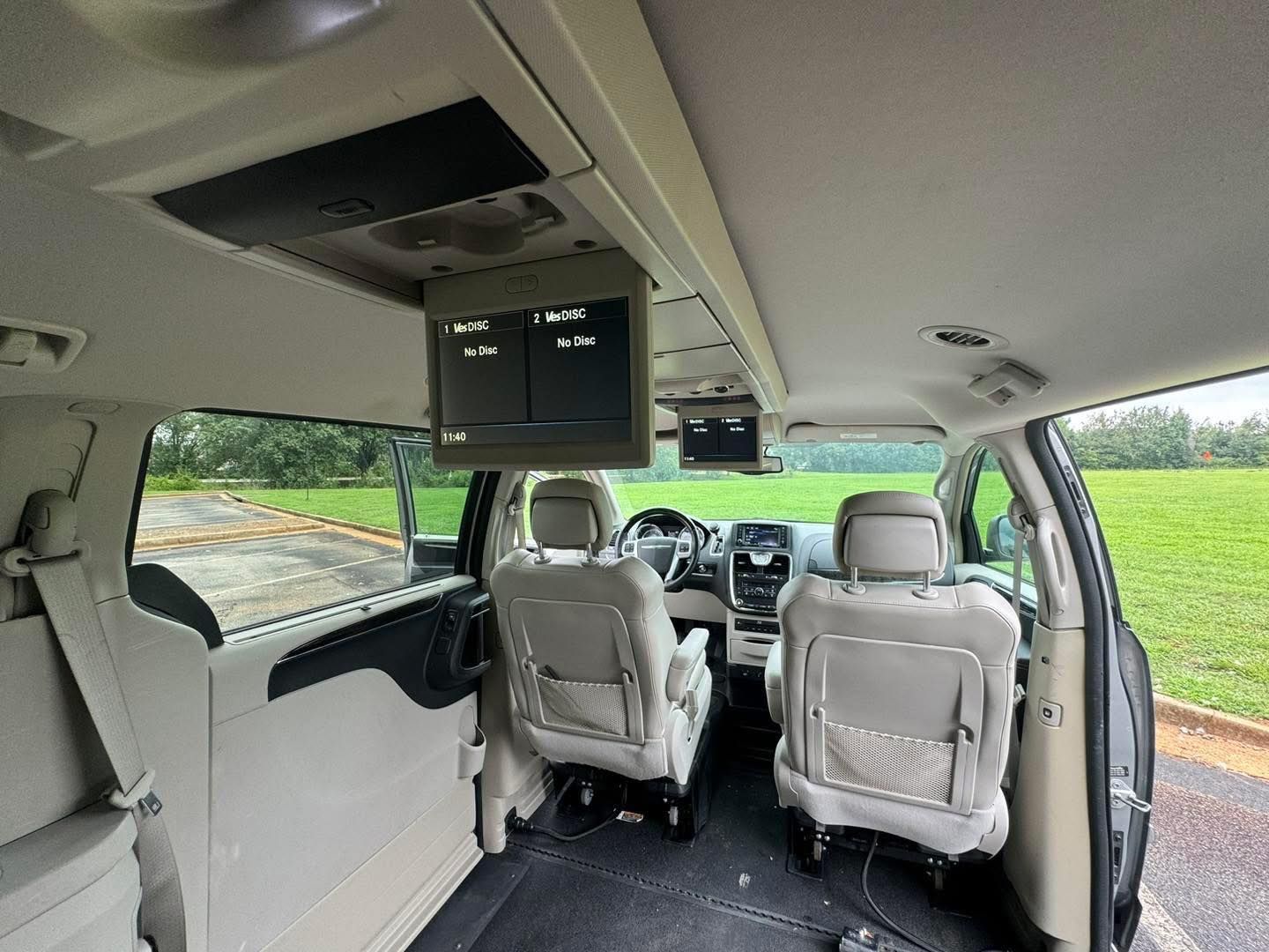 Interior of a minivan, showing front seats and overhead entertainment screens.