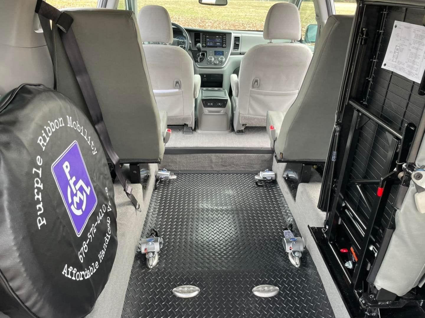 Interior of accessible van with seats removed for wheelchair access. Black floor with seat tracks. Purple mobility bag.