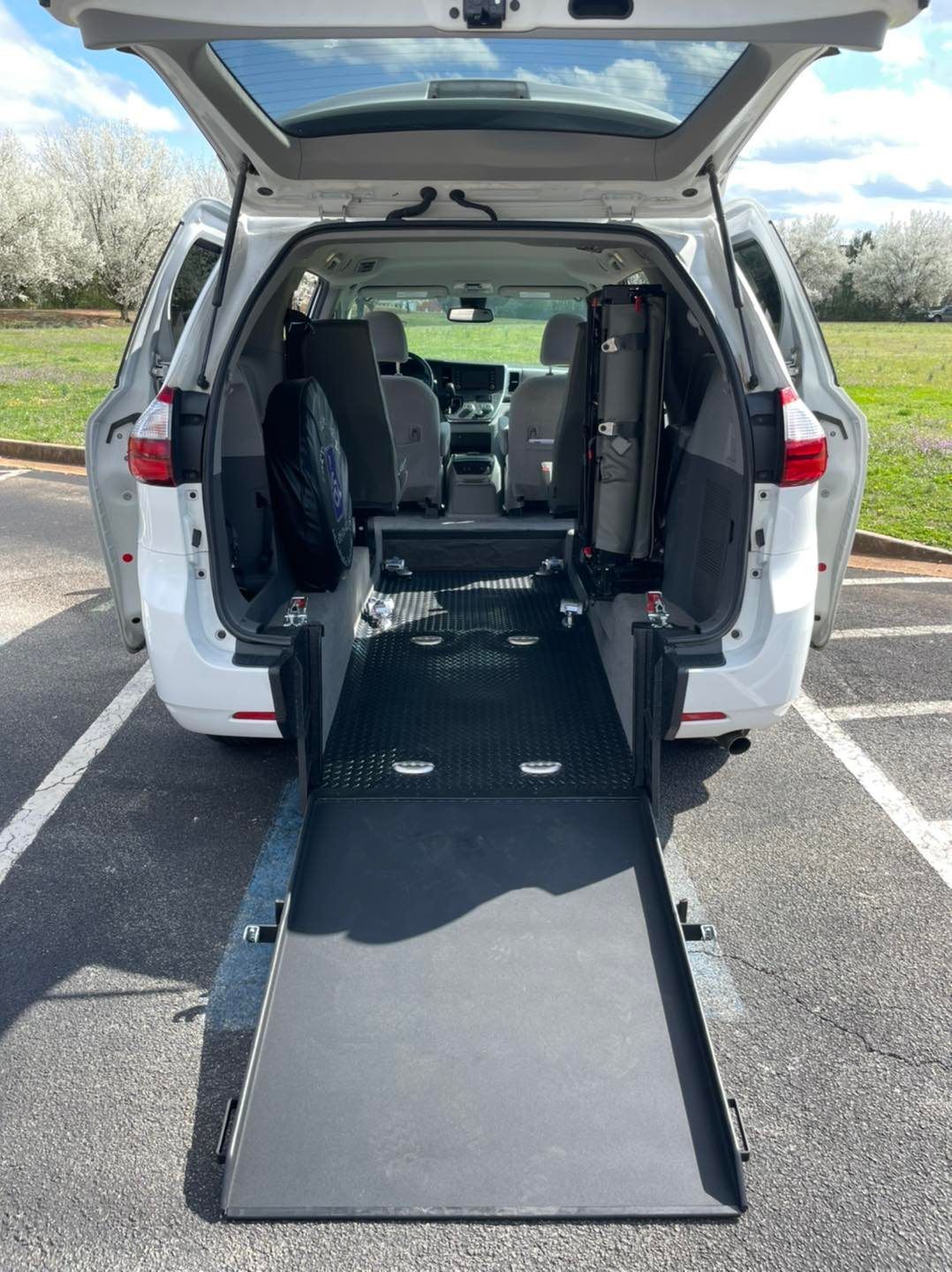 White van with ramp deployed, interior seats removed for accessibility.