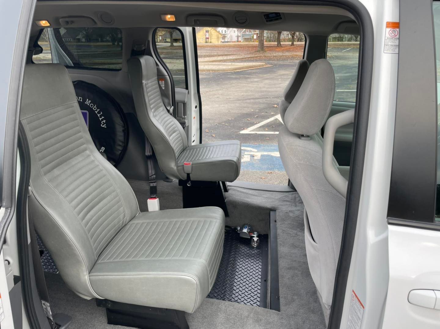 Interior view of a white van modified for wheelchair accessibility with grey seating and lowered floor.