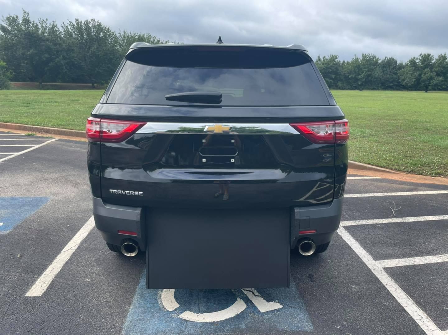 Black SUV with a wheelchair ramp extended in a handicapped parking space.
