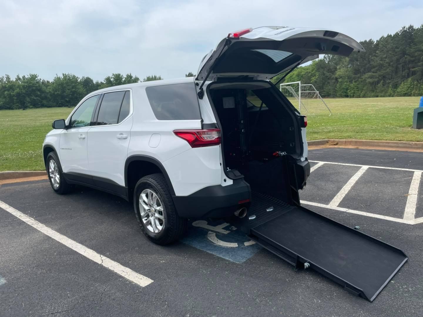 White SUV with a wheelchair ramp extended in a parking space.