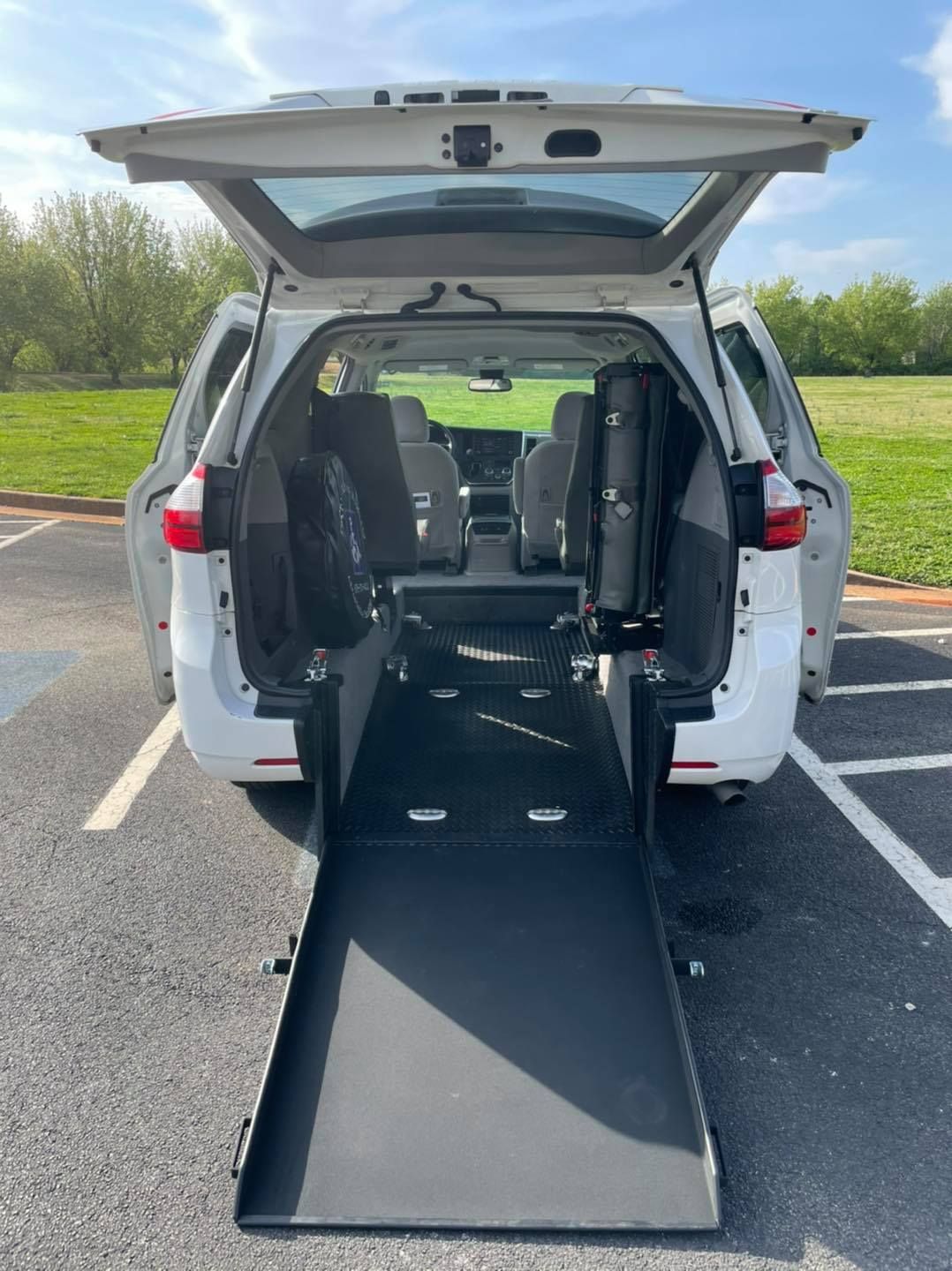 White van with ramp deployed; parked outdoors. Rear doors and lift open on paved lot.