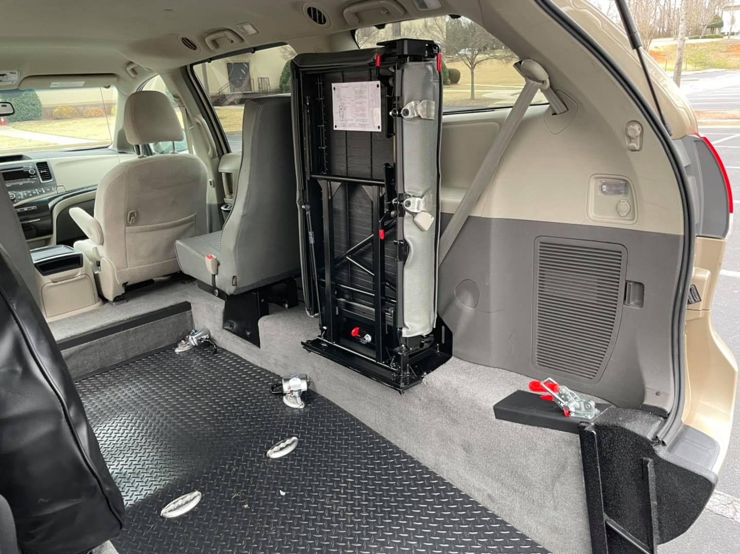 Interior of a modified minivan showing a fold-up wheelchair seat and accessible floor.