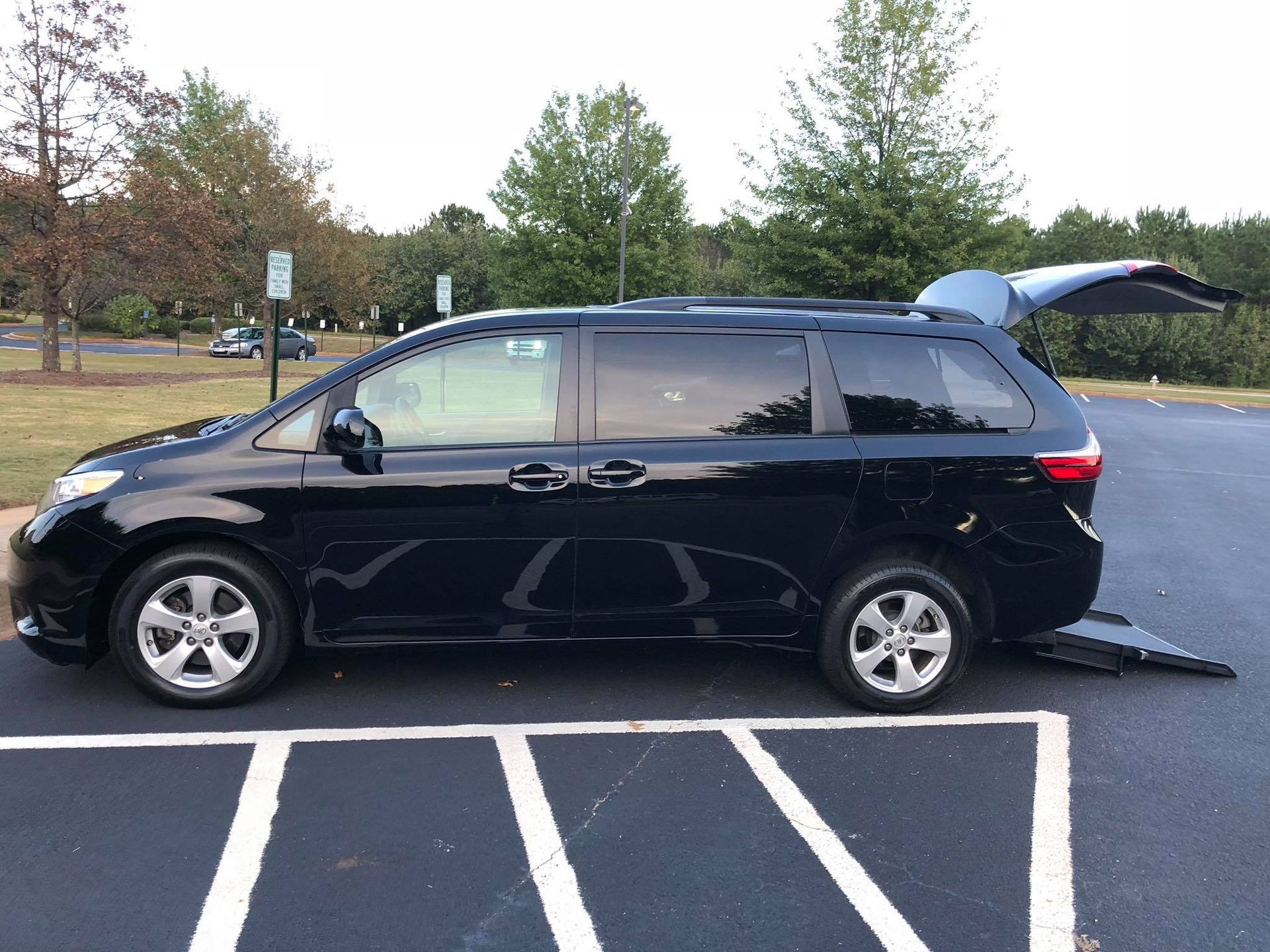 Black accessible van with ramp extended in a parking space.